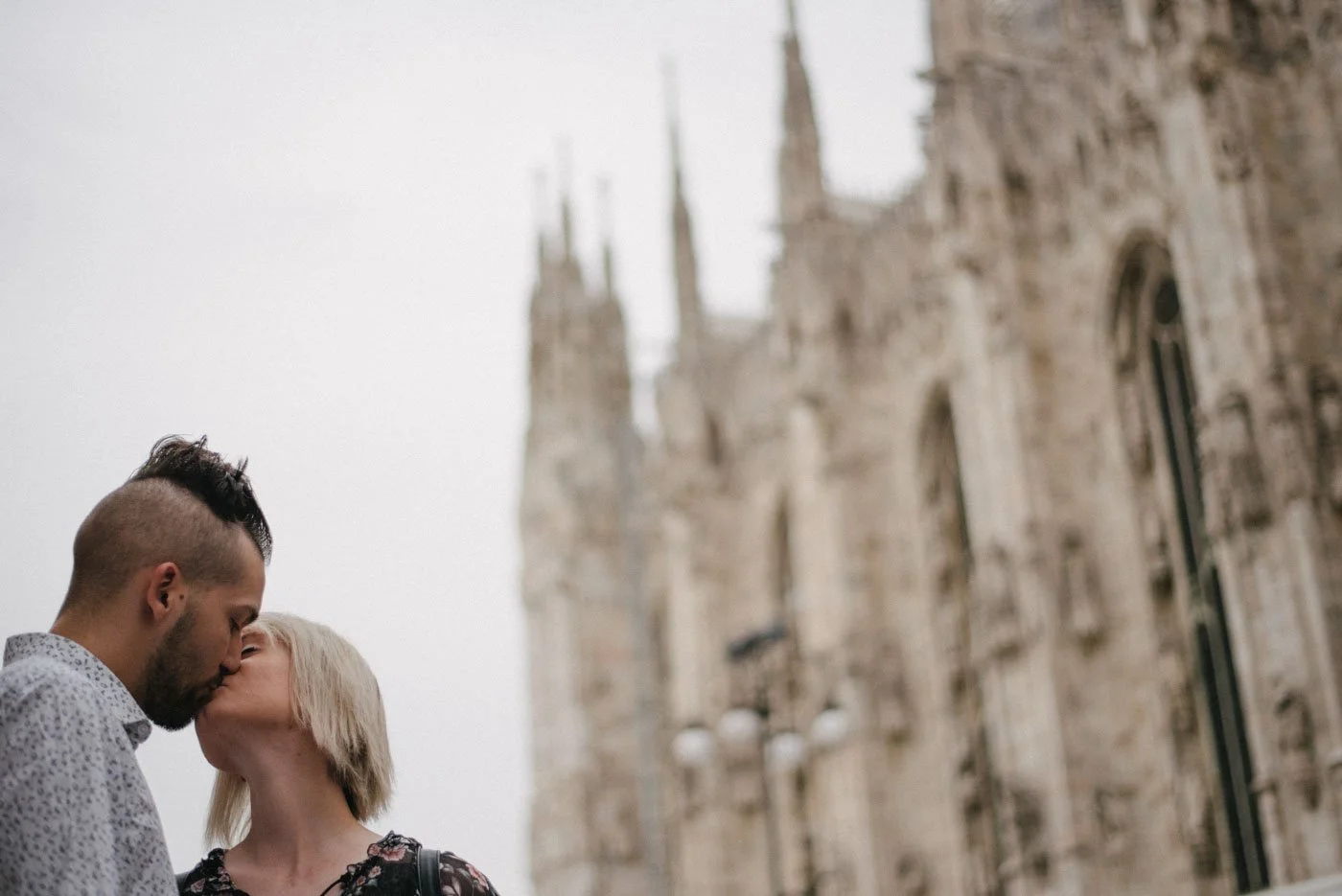 A couple kissing in front of a historic cathedral in Italy.
