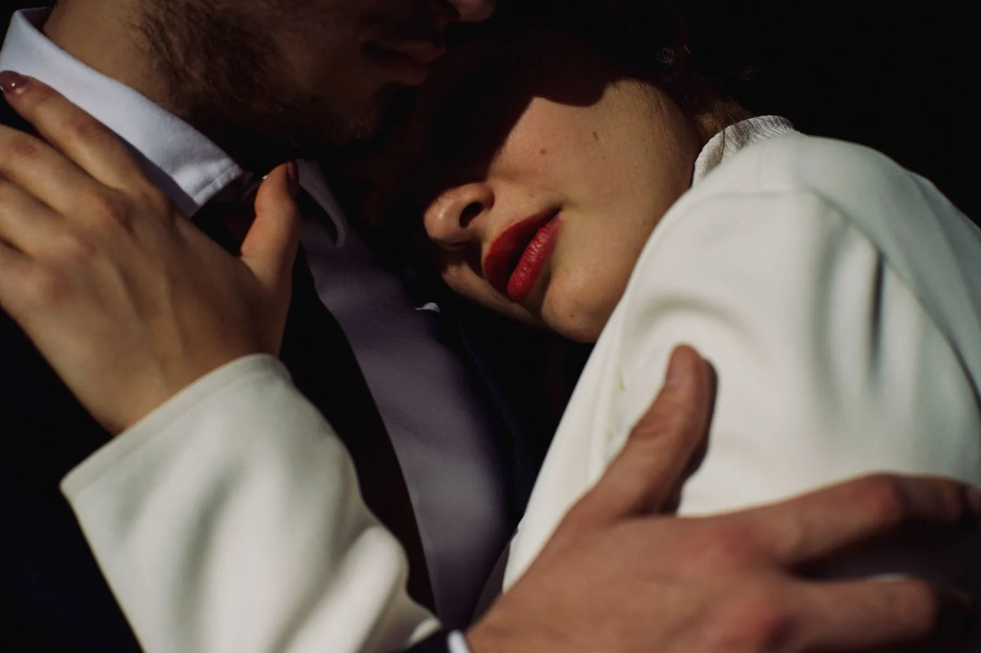 Close-up of a romantic couple embracing, with the woman resting her head on the man's chest and the man's arm around her.