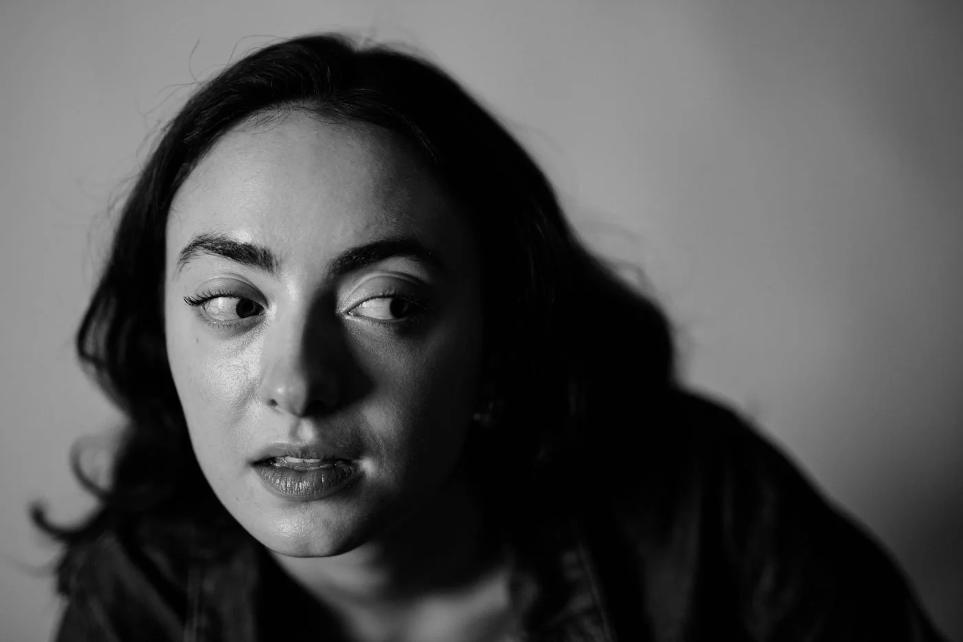 Black and white close-up portrait of a woman with dark hair, looking to her left with a contemplative expression.