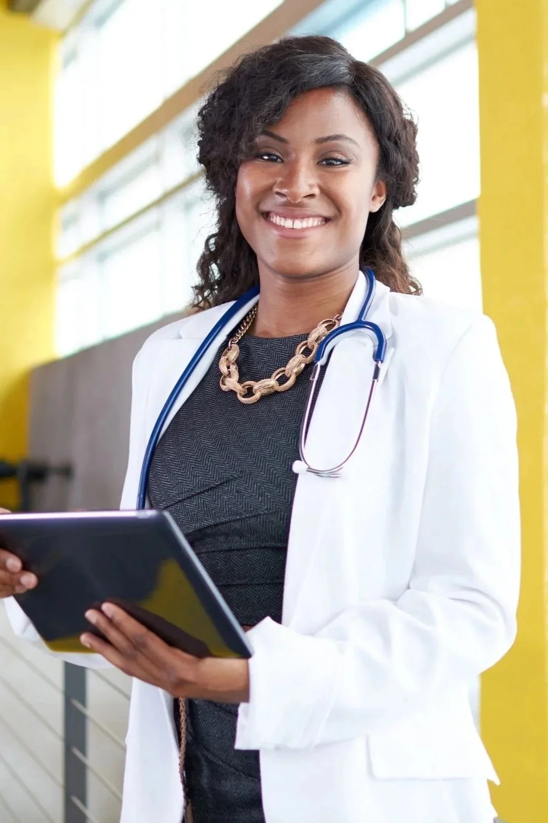 Smiling man in a white dentist coat with a tie, indoors.