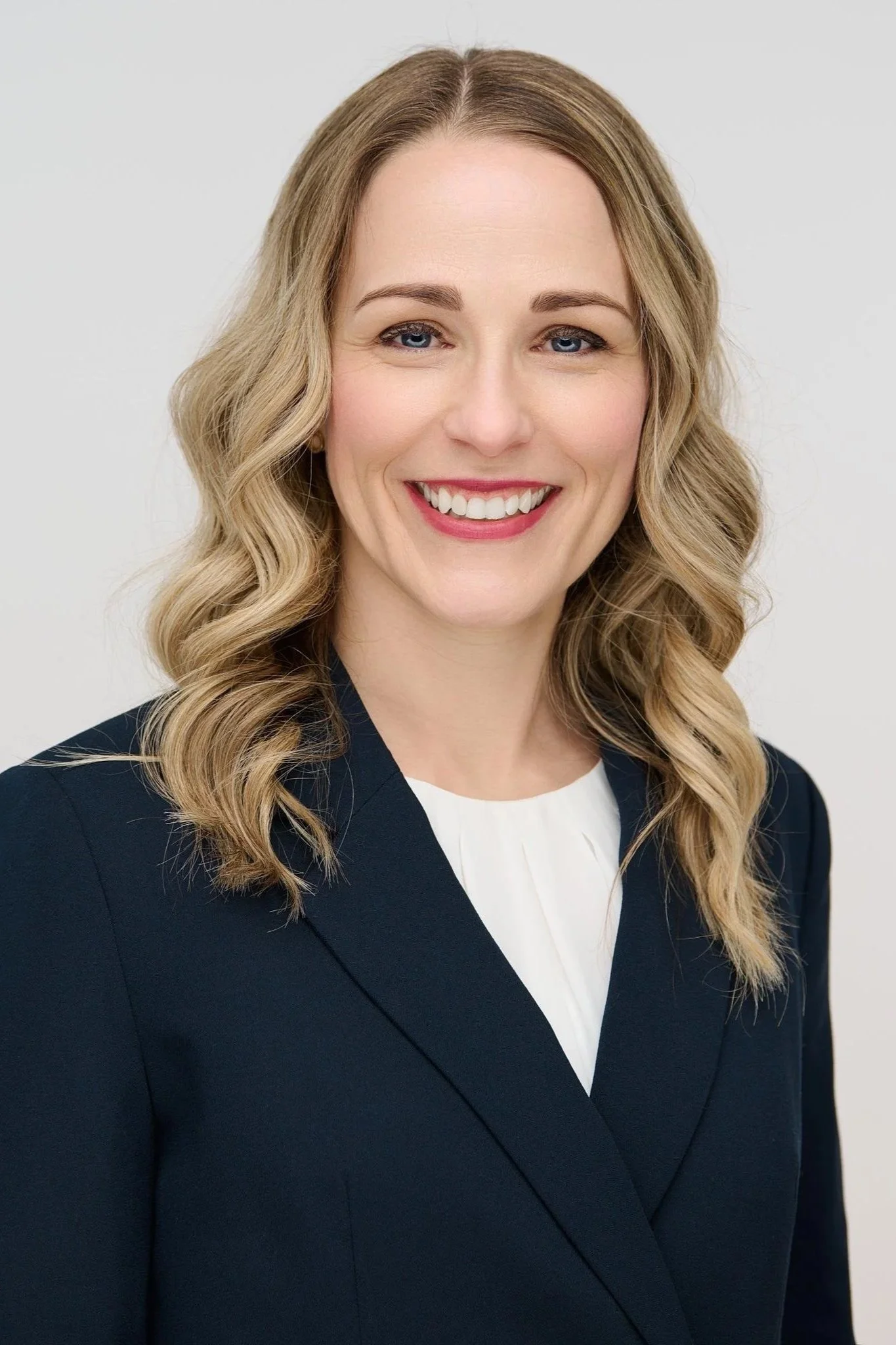Man in a blue suit and red tie against a plain background