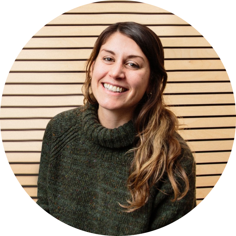 Smiling woman in green sweater against a wooden slat background