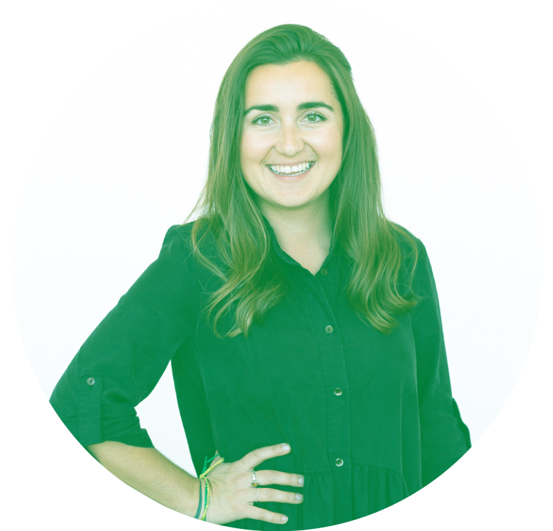 Smiling person with long hair wearing a dark shirt, standing with one hand on hip, against a white background.