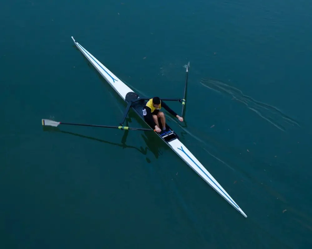 Single rower on dark water, seen from above