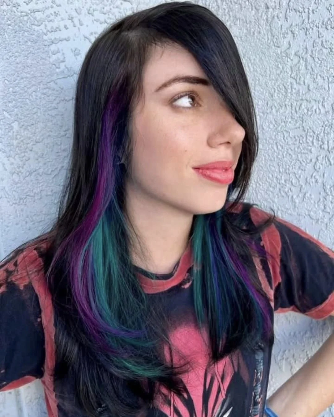 black hair with neon purple and aqua highlights peeking out medium length hair with side bangs