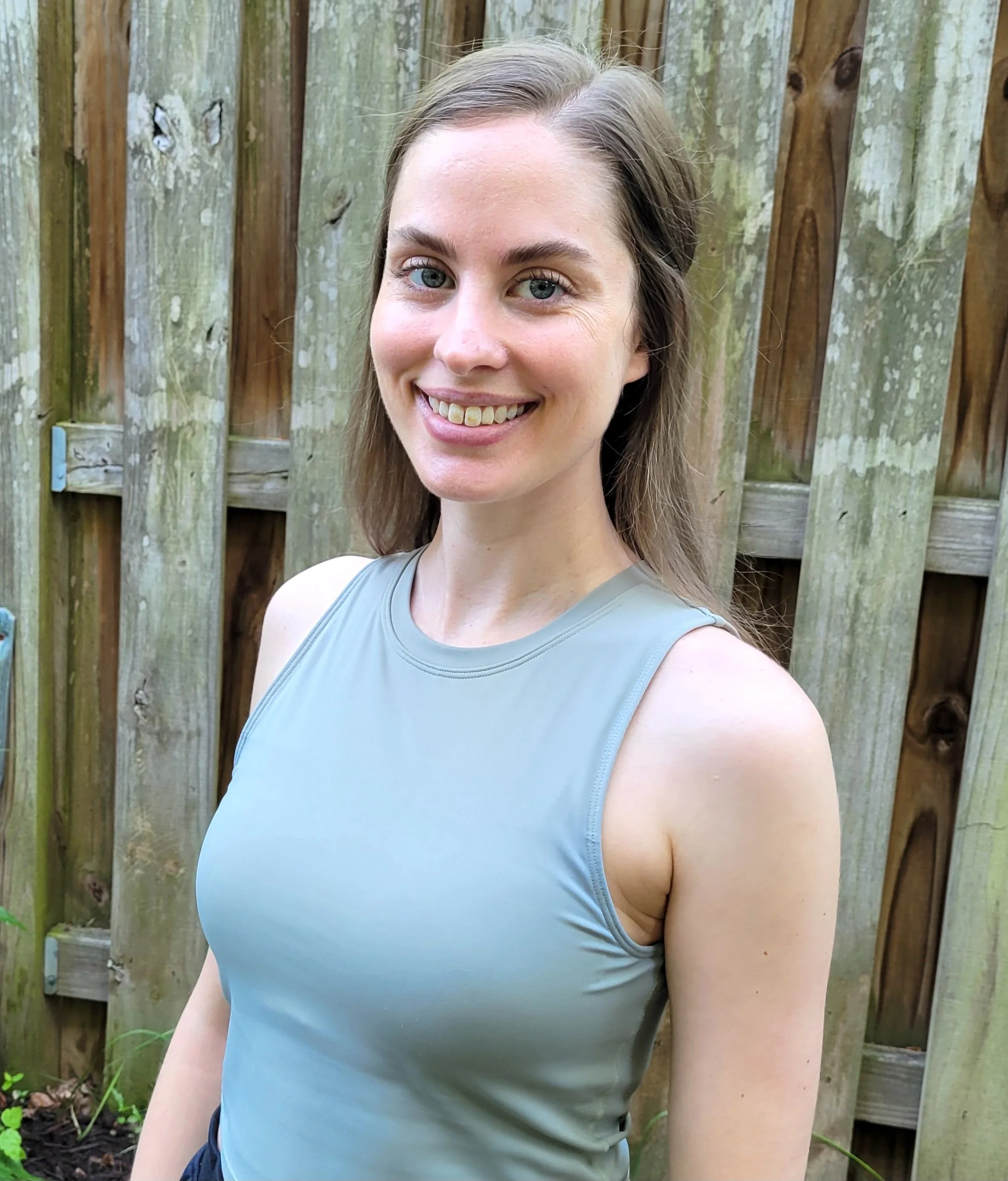 Yoga teacher in a blue tank top smiling.