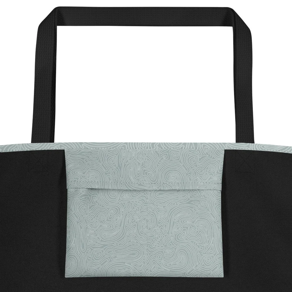 close up of the inside pocket of a sage green color topographic design on a tote bag with black handles