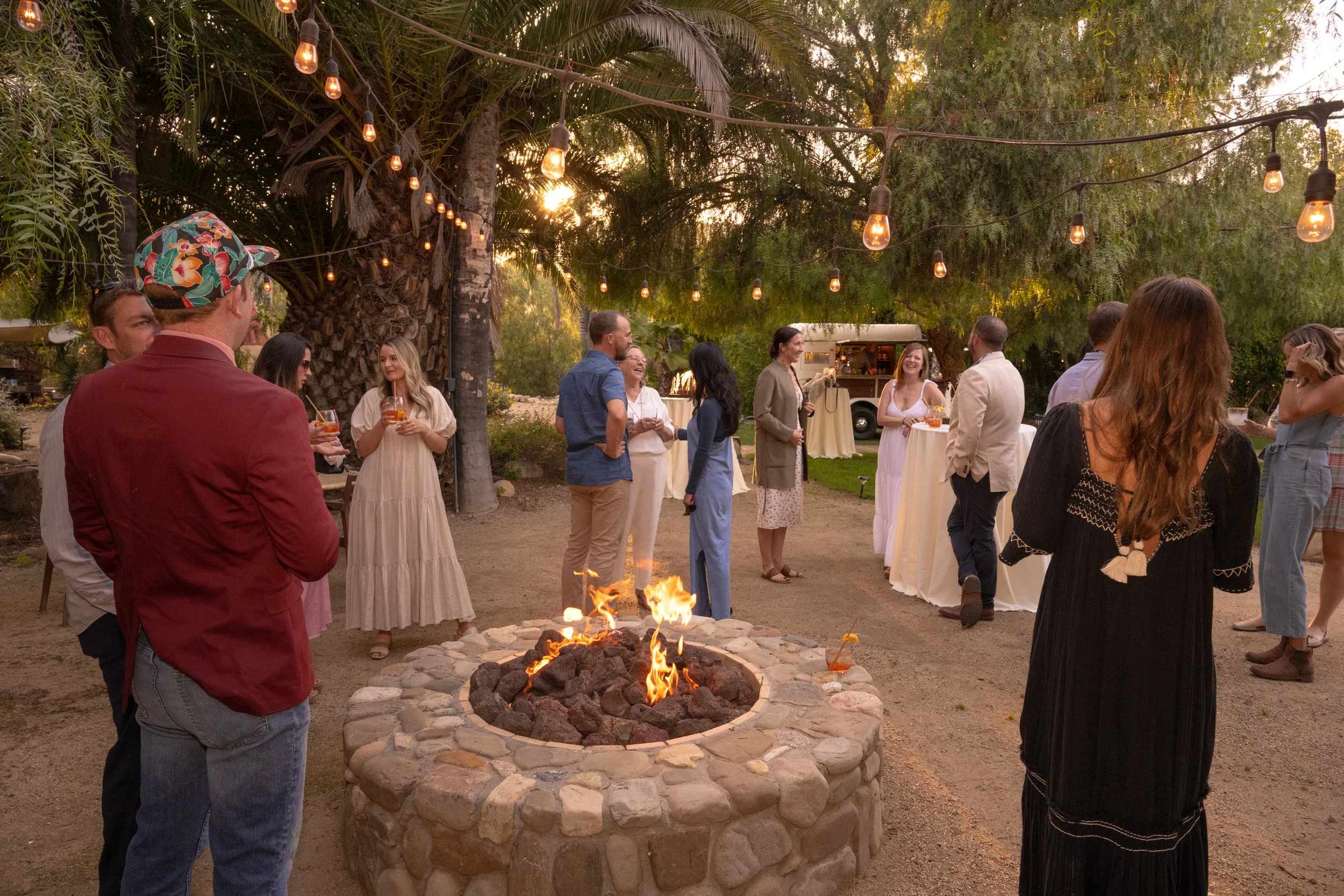 Outdoor gathering with people socializing around a fire pit