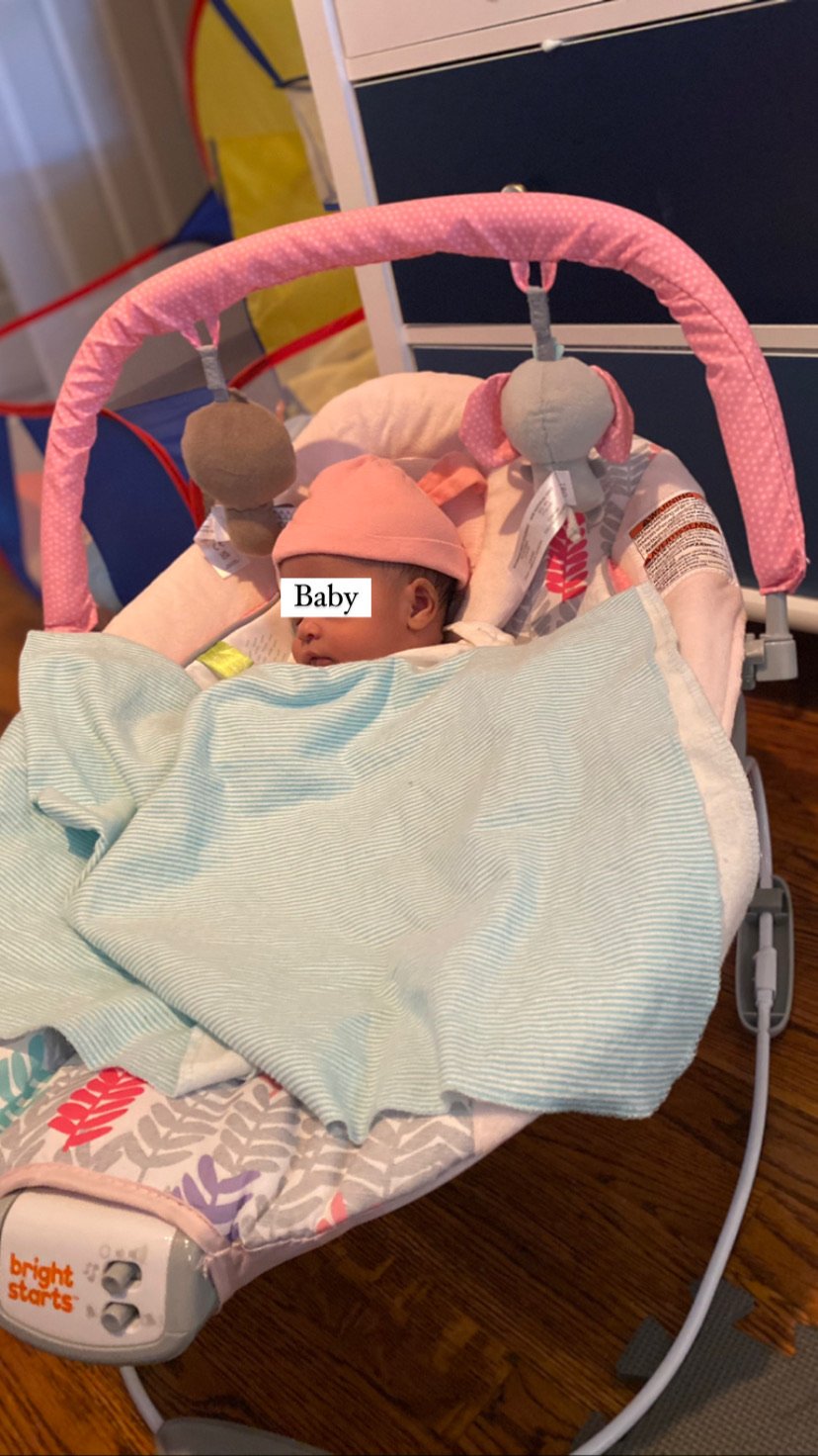 Infant sleeping in a baby swing with a pink hat and blue blanket
