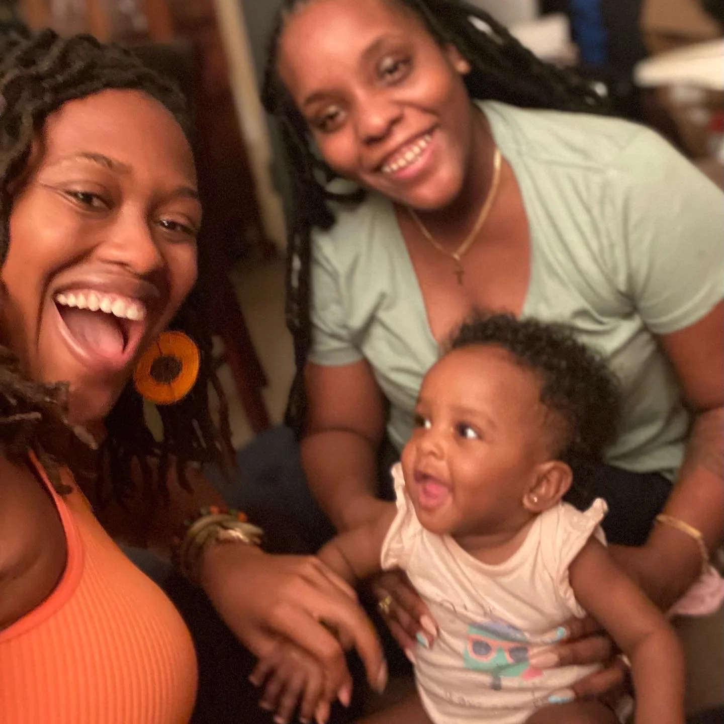 Three people smiling, including a baby, in a joyful and candid moment.