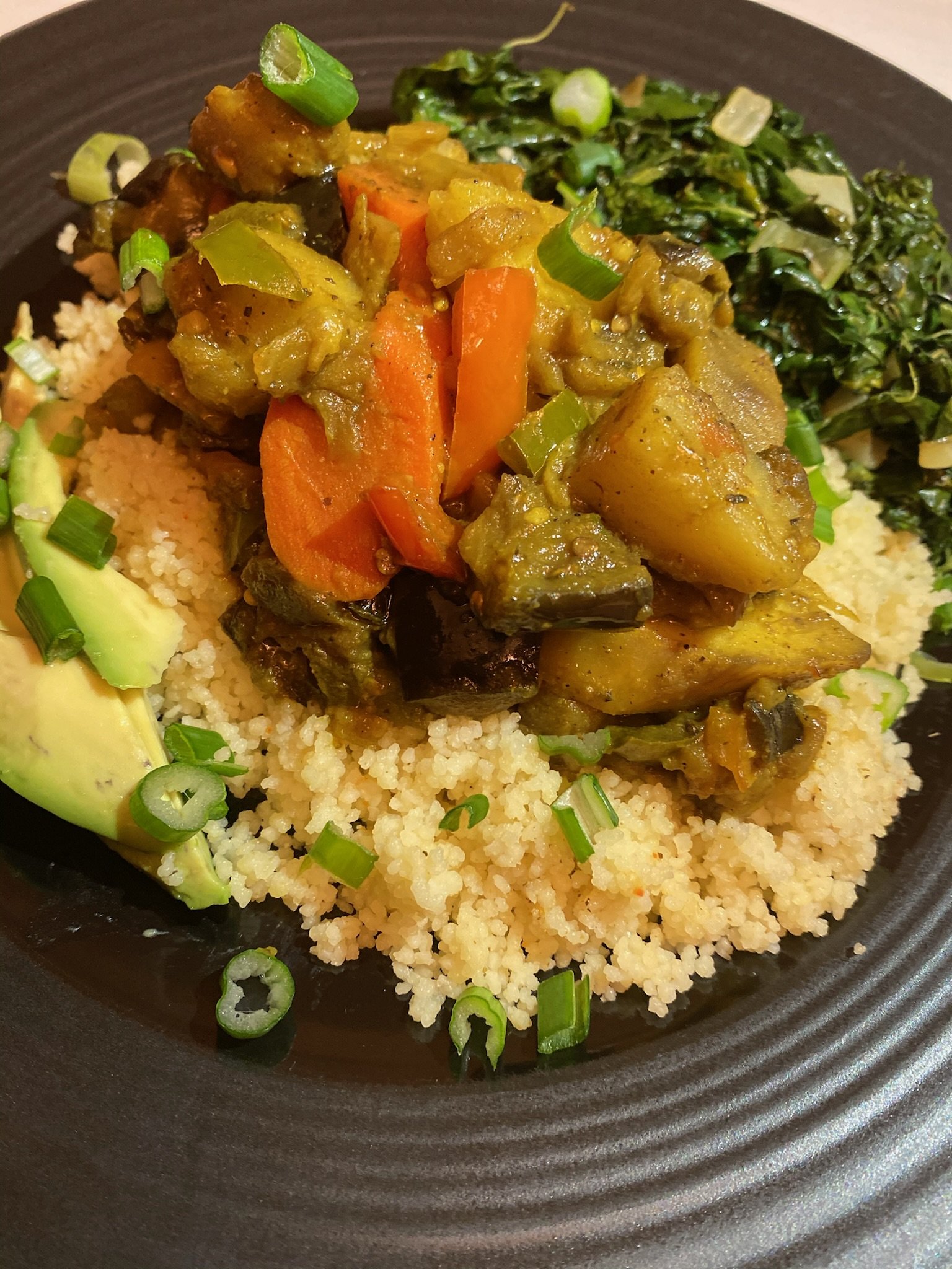 Plate of couscous with mixed vegetables, avocado, and greens
