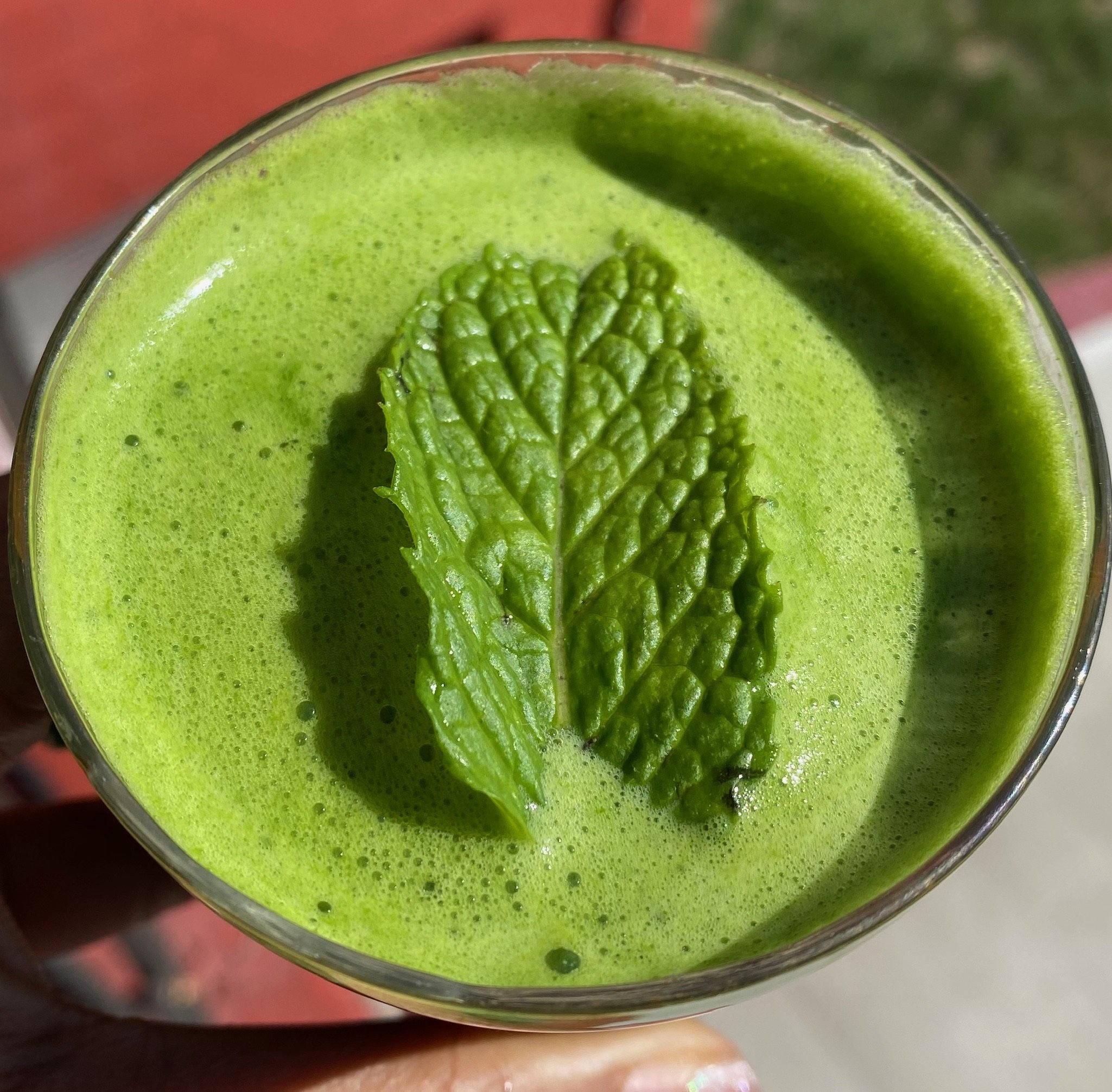 Green smoothie with mint leaf garnish in a glass