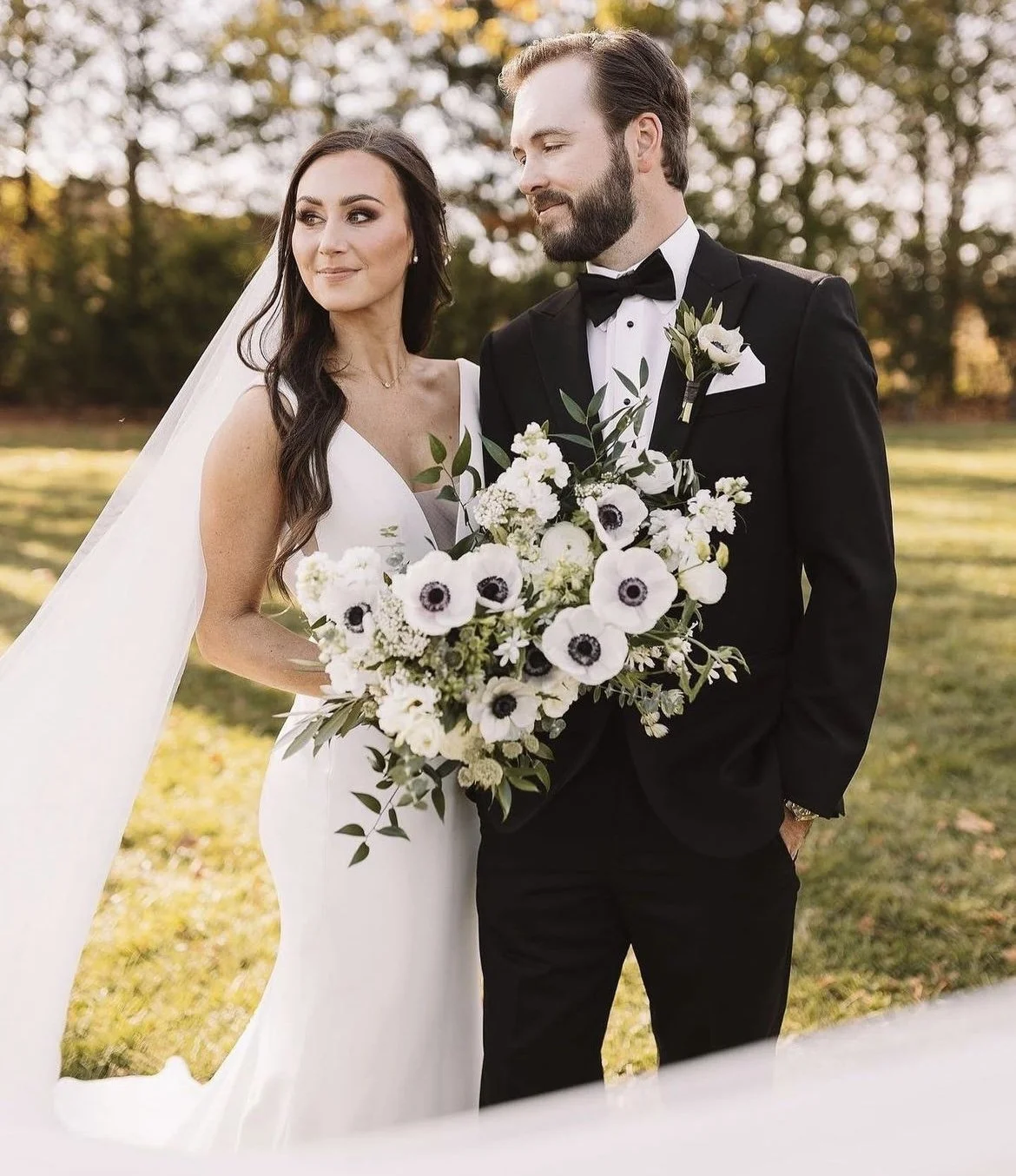 Bride and groom pose outdoors with bouquet
