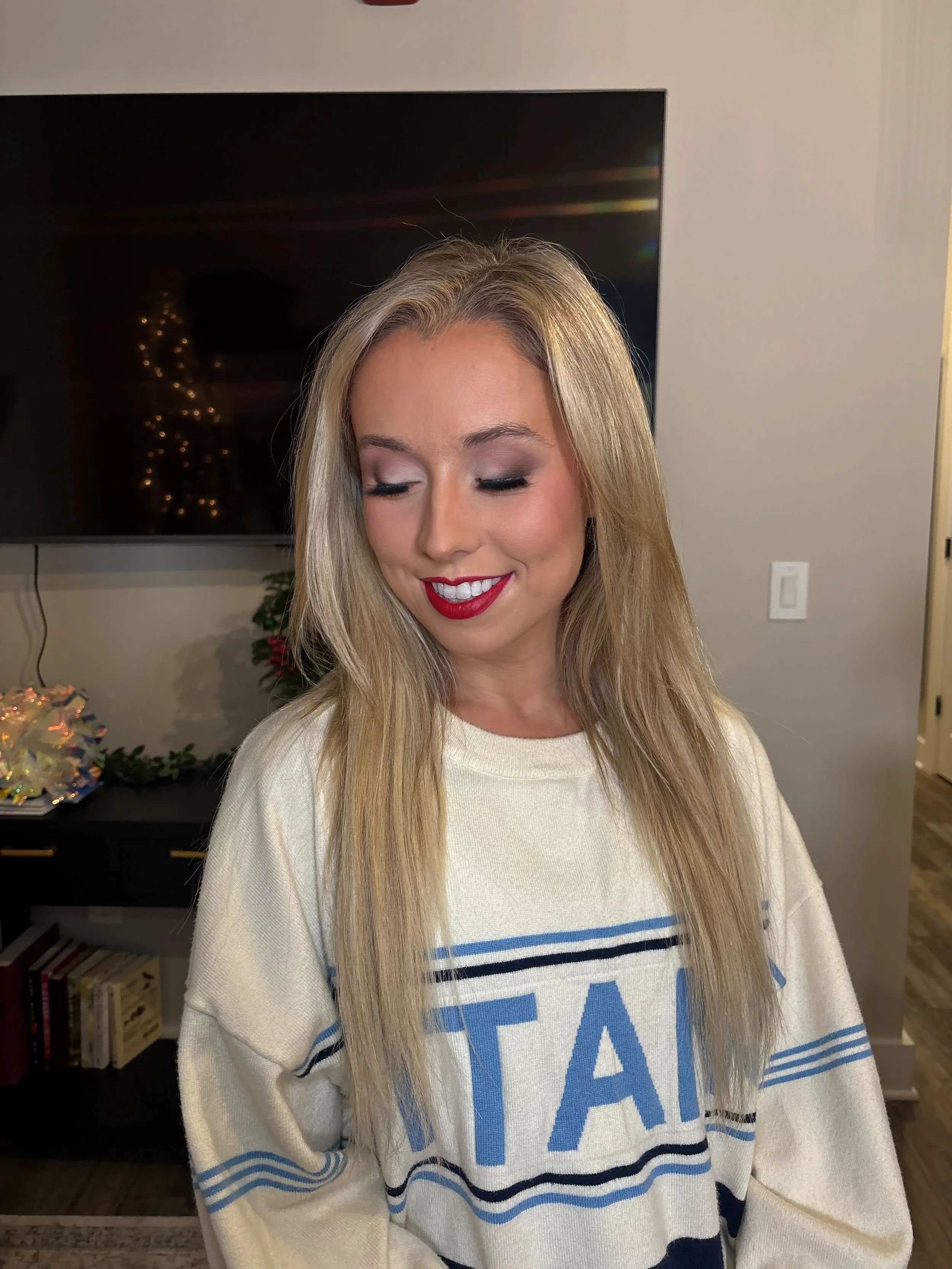 Blonde woman wearing holiday red lip makeup with soft neutral eyes and rosy cheeks, created for a Christmas Titans game by Glam Up Nashville.