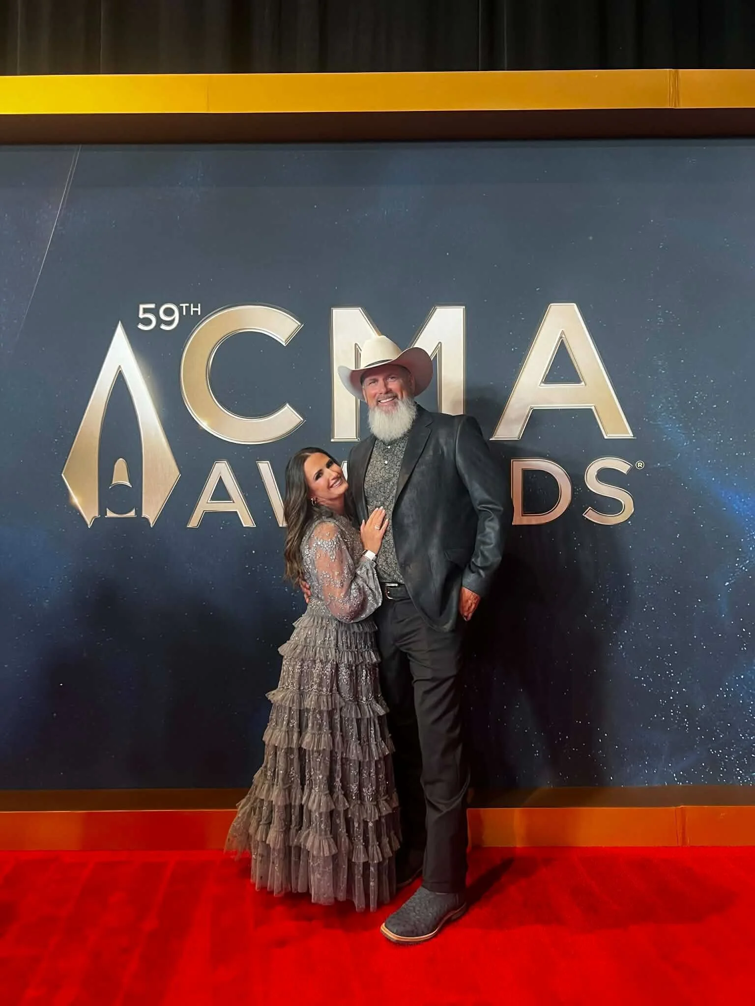 Woman wearing soft glam makeup with defined eyes, glowing skin, and a subtle lip while standing on the CMA Awards red carpet.