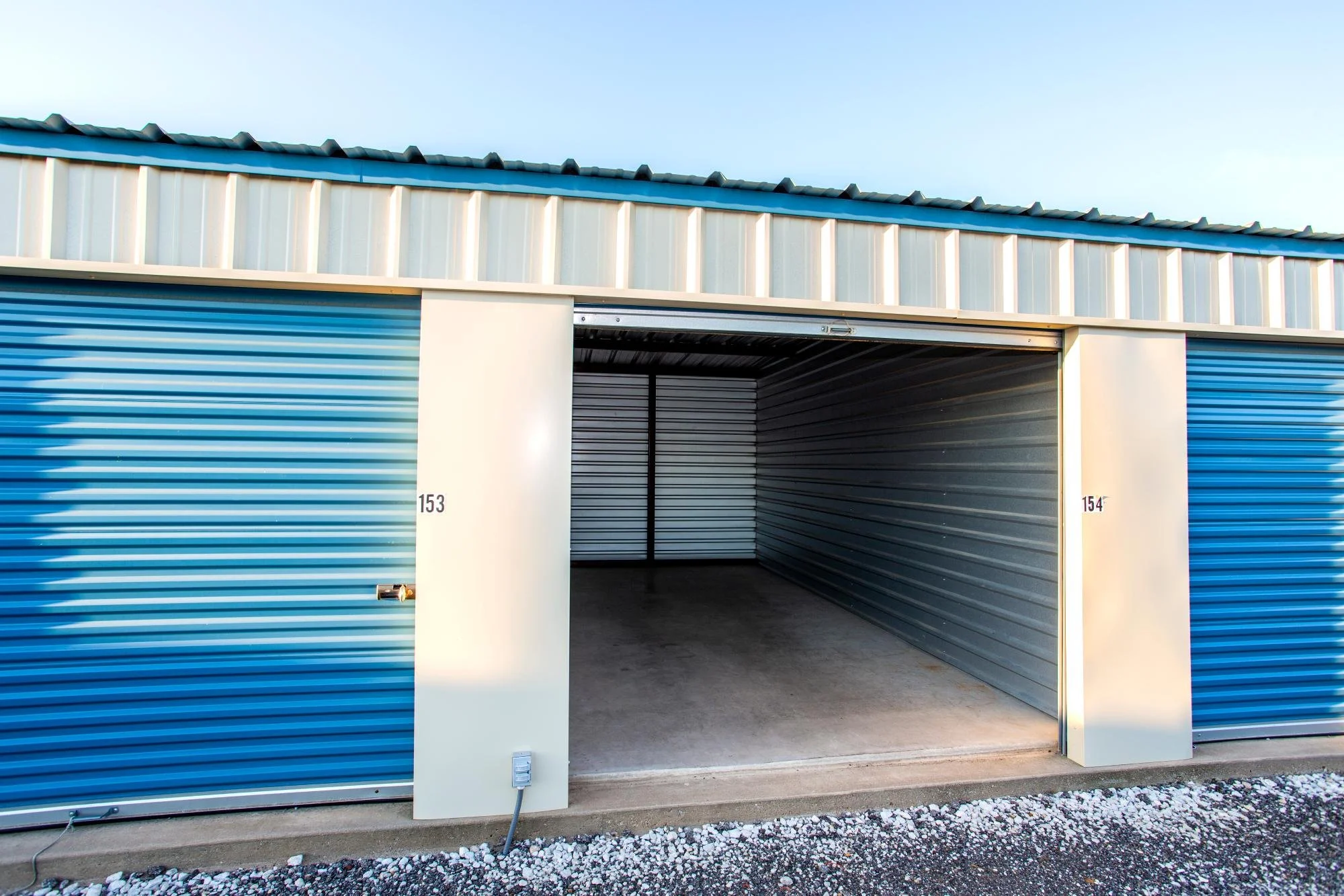 Open storage unit with metal walls and concrete floor, units numbered 153 and 154