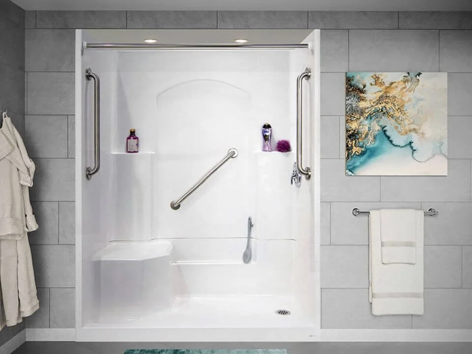 Accessible shower with grab bars, two bottles of shower products, a towel rack with a white towel, and abstract artwork on a tiled wall.