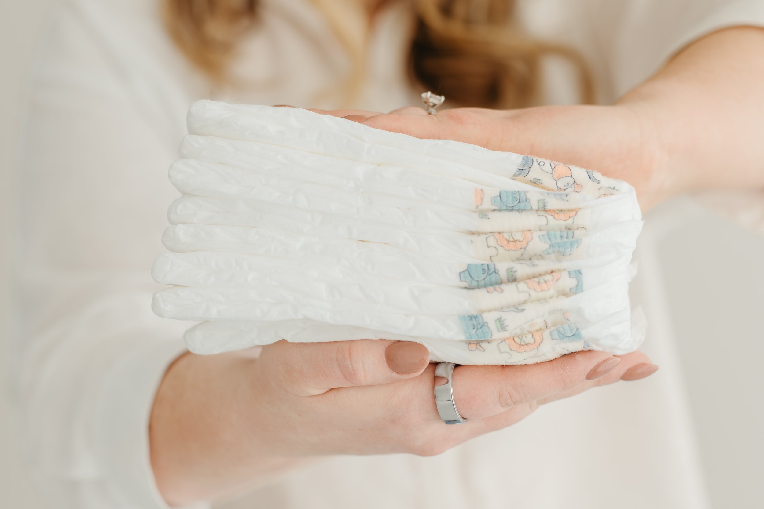 A hand holding a stack of colorful diapers.