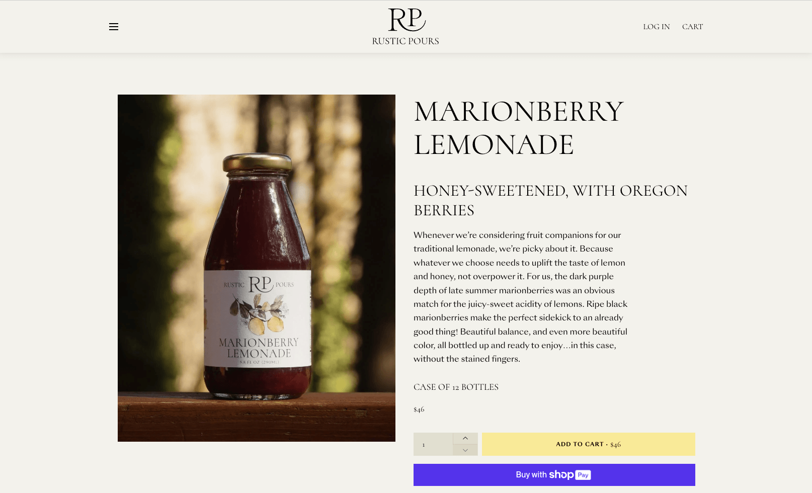 Bottle of Marionberry Lemonade by Rustic Pours with illustration of blackberries and lemons on the label, placed outdoors with a blurry forest background.