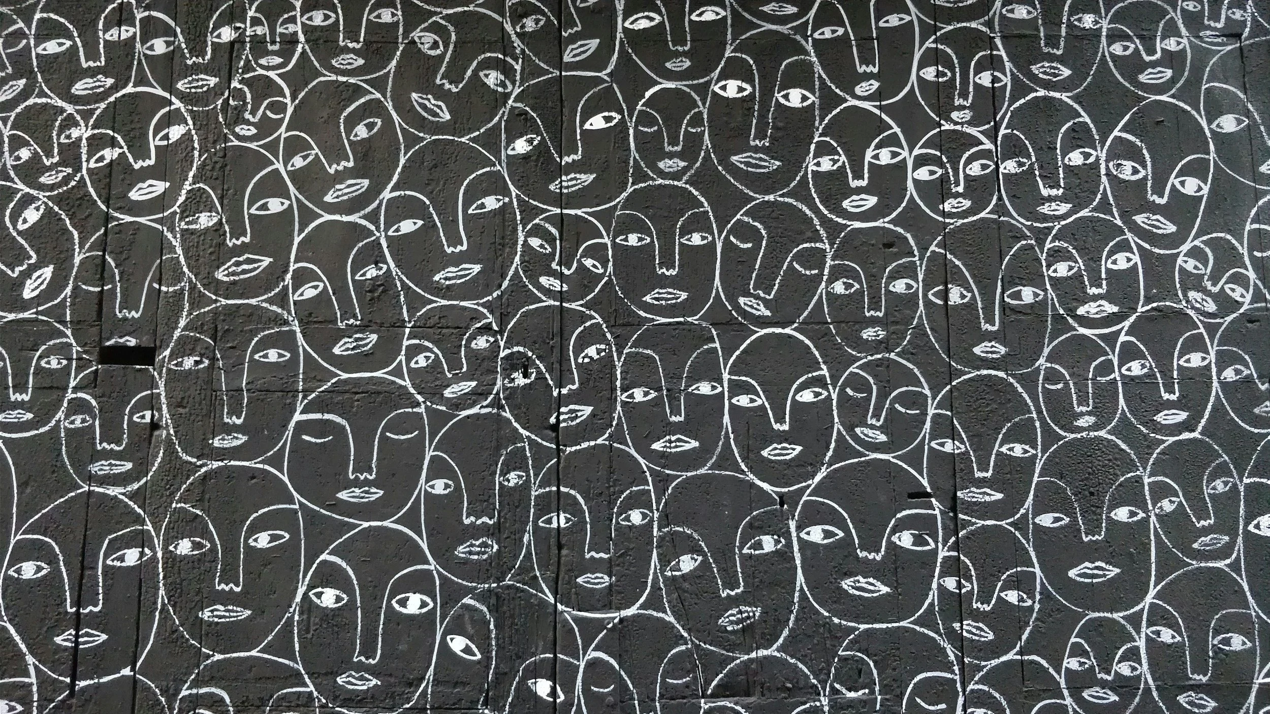 mural of line-drawn faces on a black background