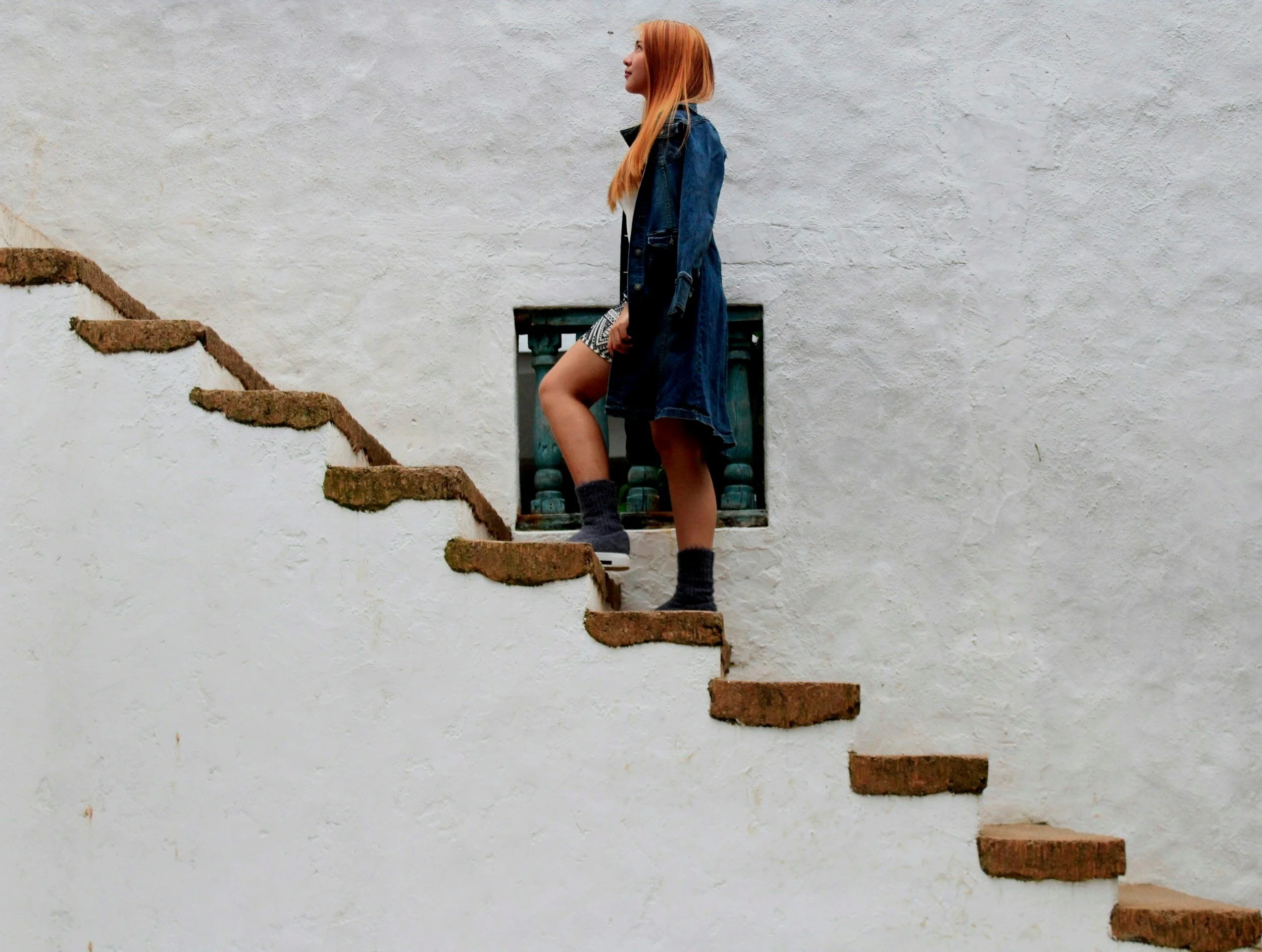 Person walking up outdoor stairs with white wall background.