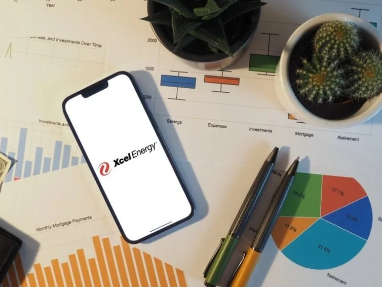 Mobile phone with Xcel Energy logo lying on top of EV infrastructure analysis documents.