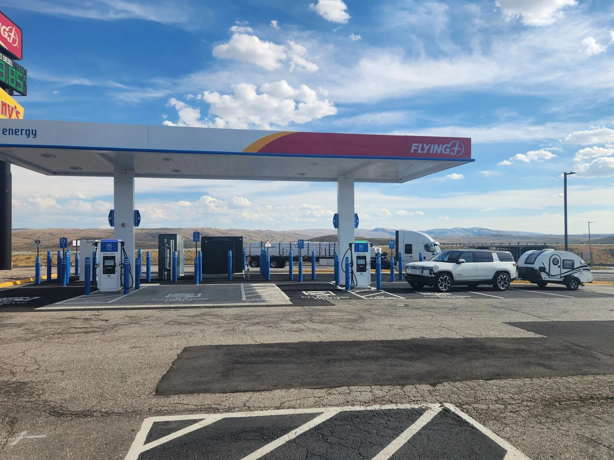EV towing a teardrop trailer at a charger