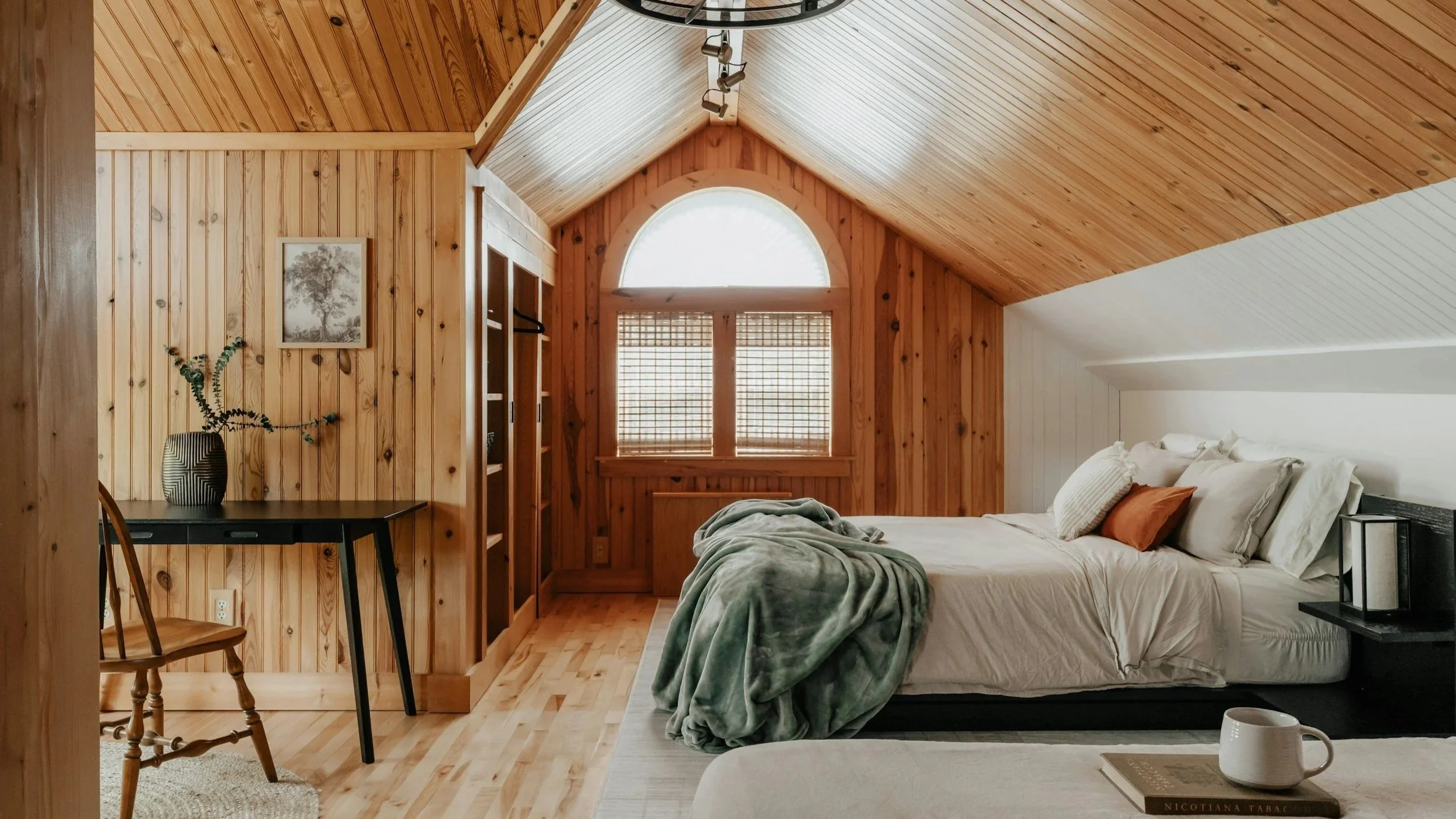 Bright cabin-style vacation rental bedroom with a wood ceiling and a freshly made bed