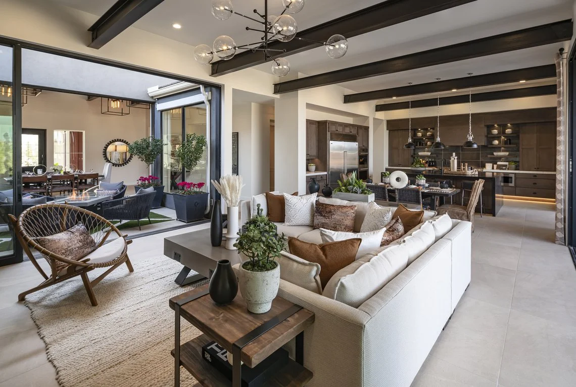 Bright, tidy open-concept living room and kitchen with a white sectional and wood beams