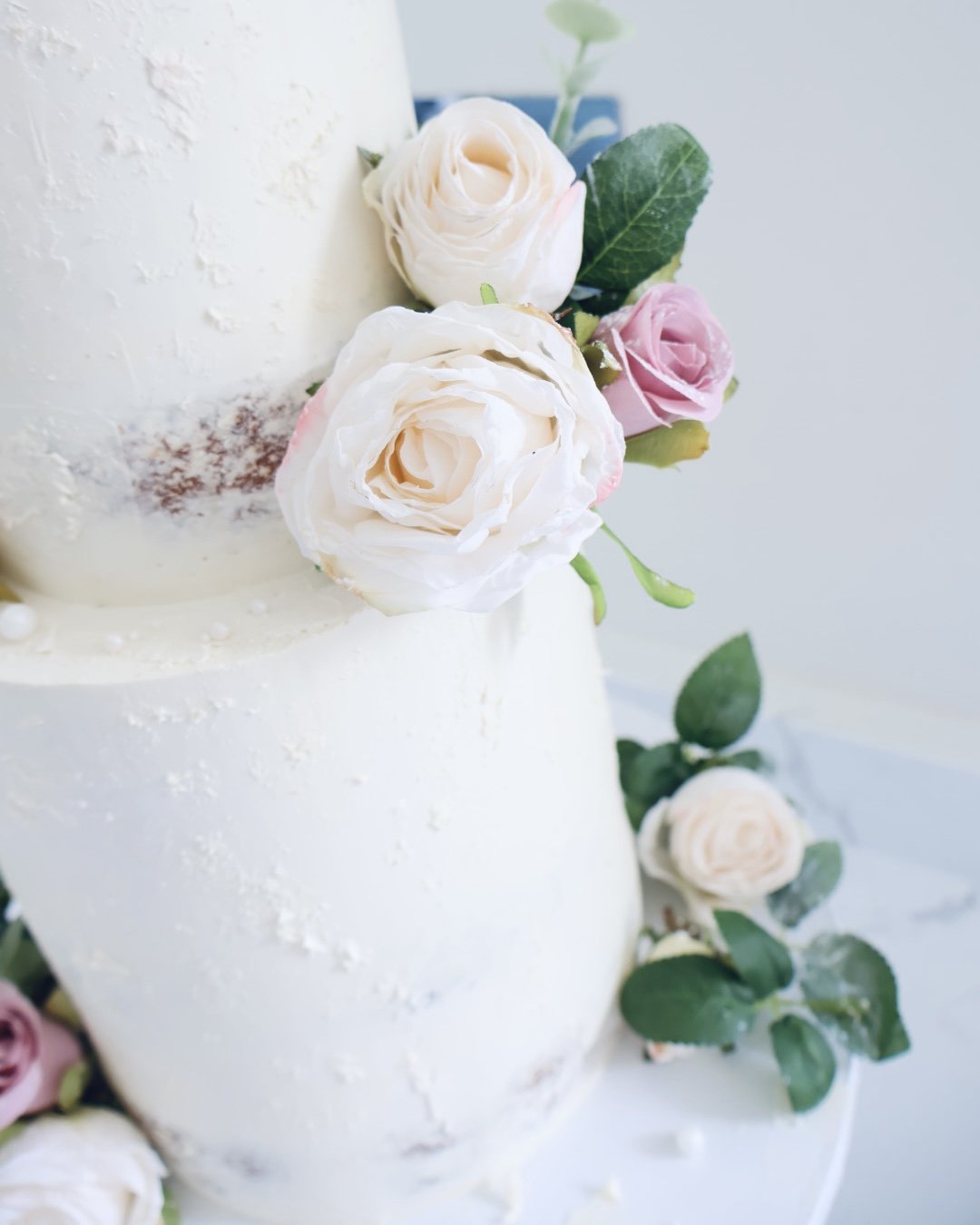 two-tier-white-semi-naked-ganache-wedding-cake-with-artificial-flowers-close-up.JPG