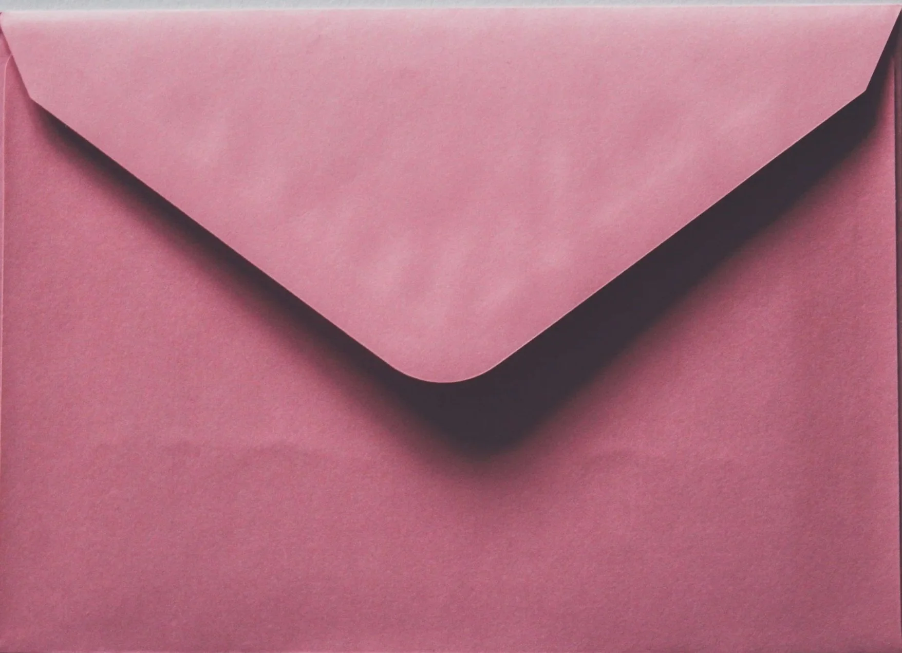 A pink paper envelope with a triangular flap.