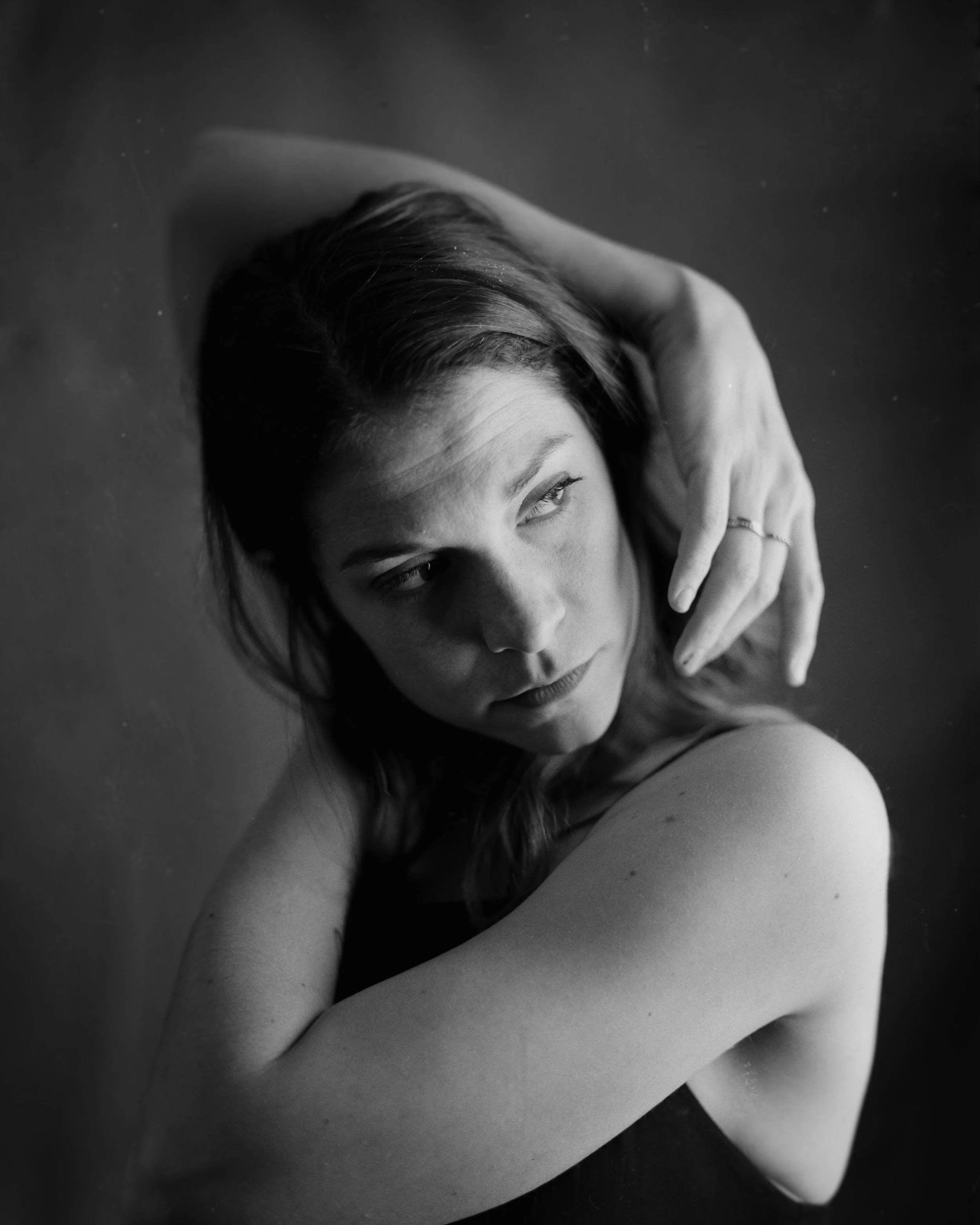 Black and white portrait of a woman with her arms crossed, looking to the side, with wet hair and a contemplative expression.