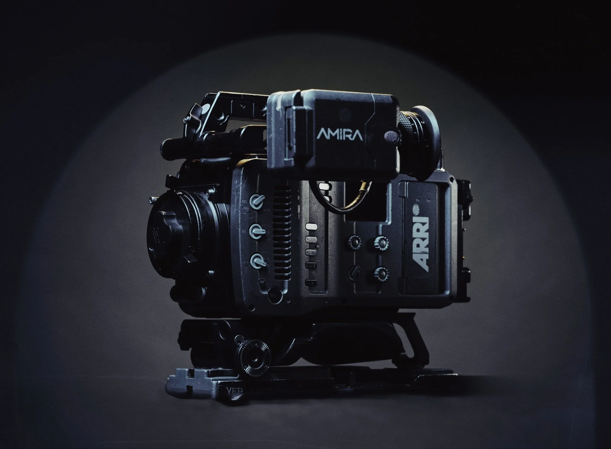 Close-up of a professional cinematic camera on a black surface with focused lighting, labeled 'ARRI' and 'AMIRA'.