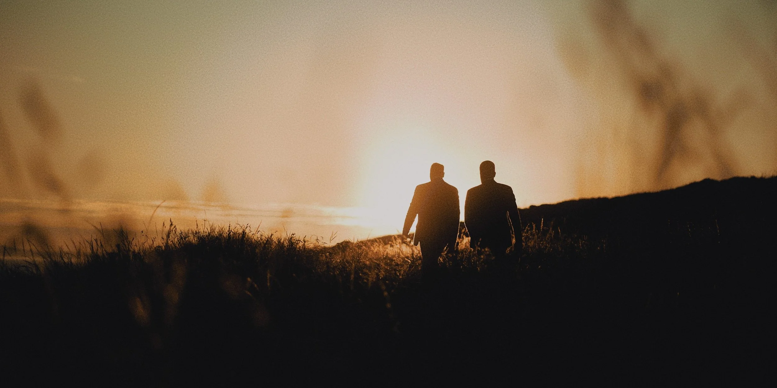 LGBTQ+ couple walking in to the sunset.jpg