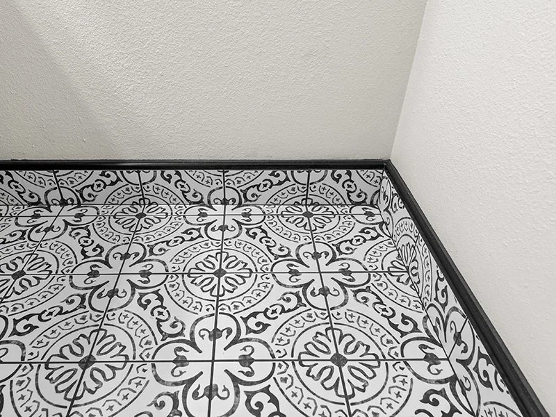 Black and white repeating tile design on ceramic floor tiles with corner edge