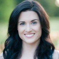 Portrait of a woman with dark hair, smiling outdoors