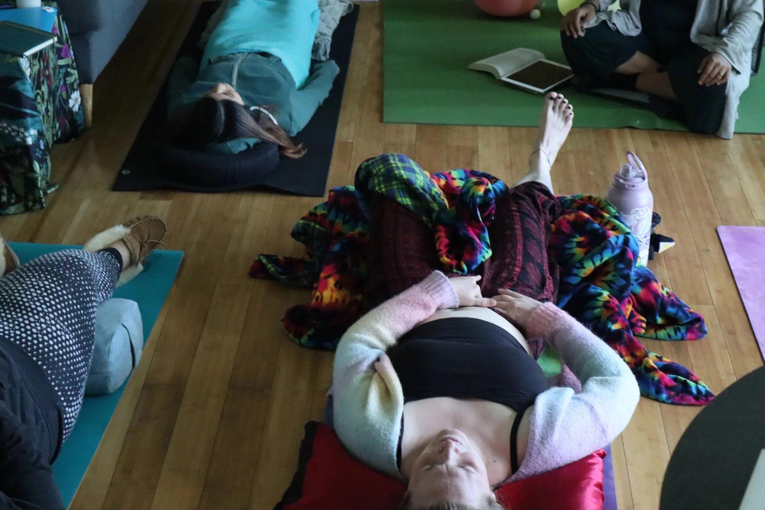 Two women in a somatic breathwork journey at The Spiral, a private women's group in Sacramento, with one woman resting her hands on her body in self-connection