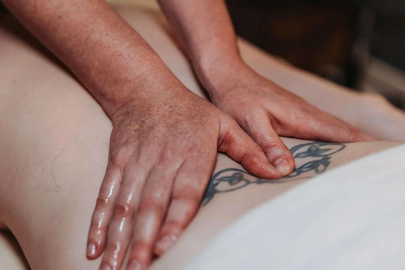 A closeup of two hands massaging the lower back