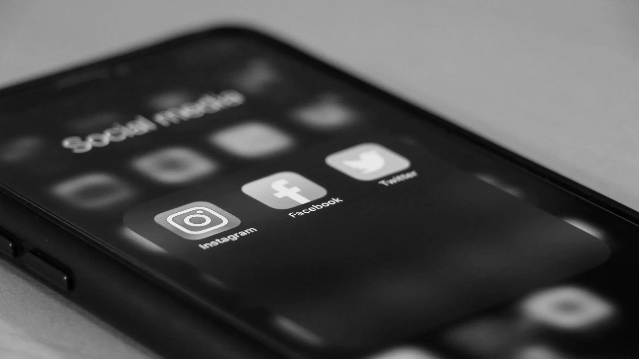 Close-up of a smartphone screen showing social media icons for Instagram, Facebook, and Twitter.