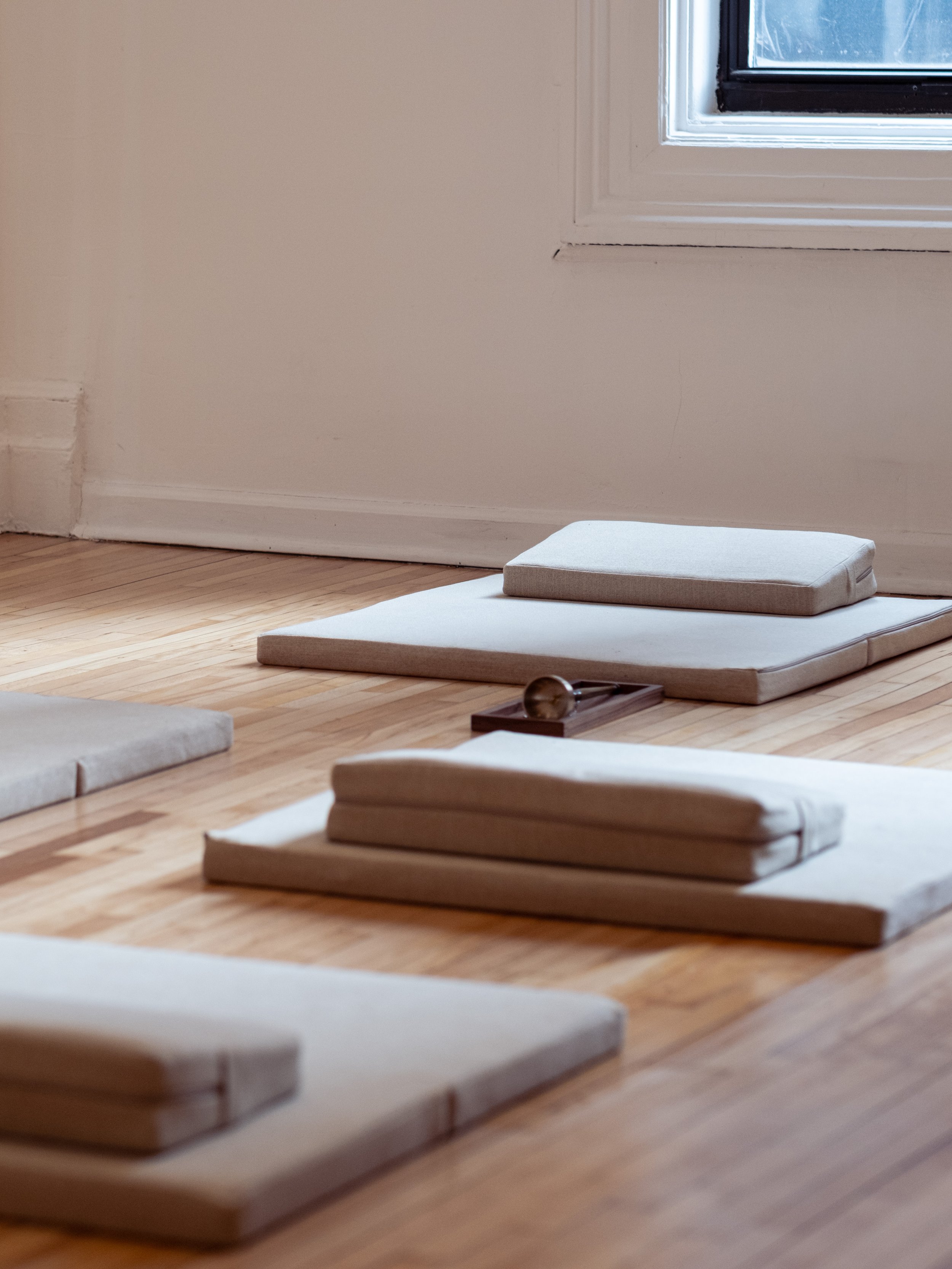 Meditation cushions arranged on the wooden floor at Teasthetic.