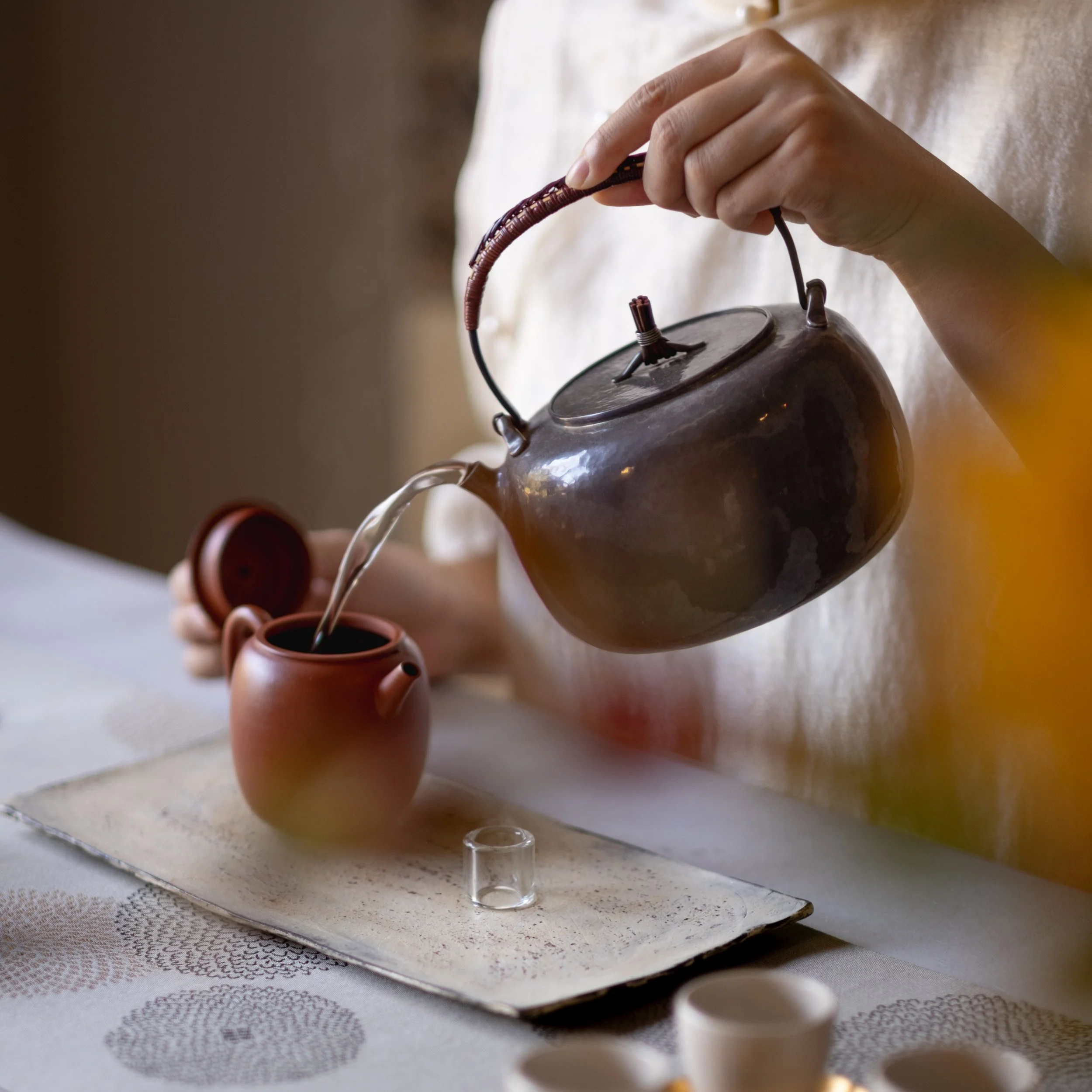 Water being poured from a kettle into a clay teapot during a Chinese tea ceremony at Teasthetic.