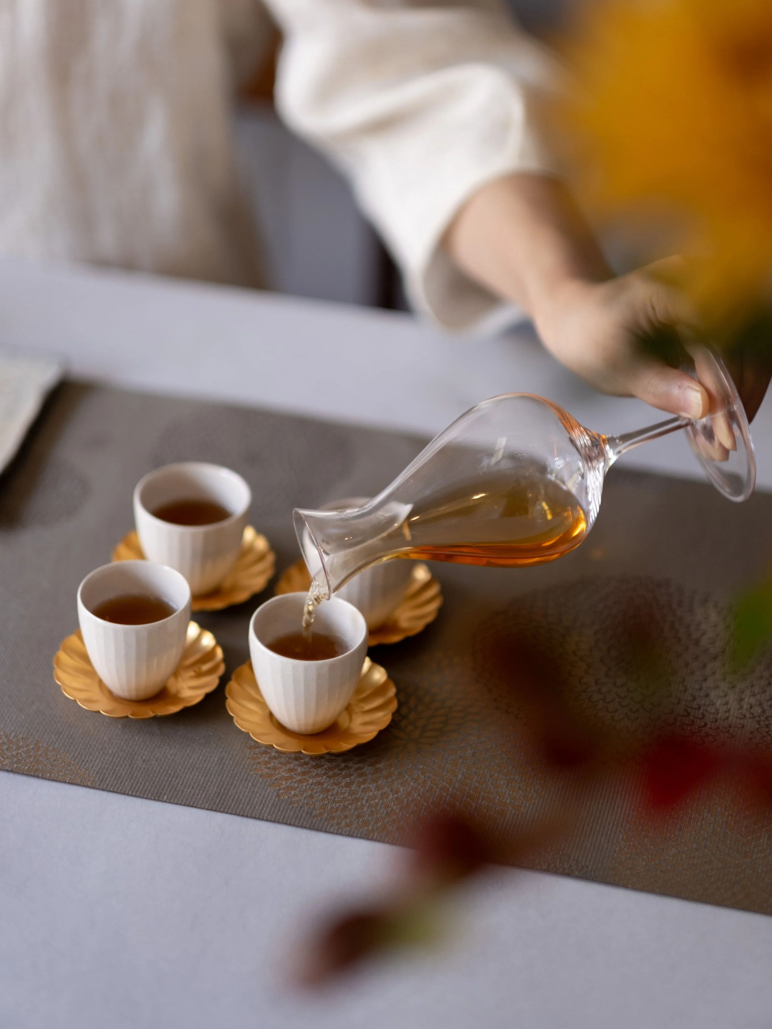 Tea being poured into white cups during a Chinese tea ceremony.