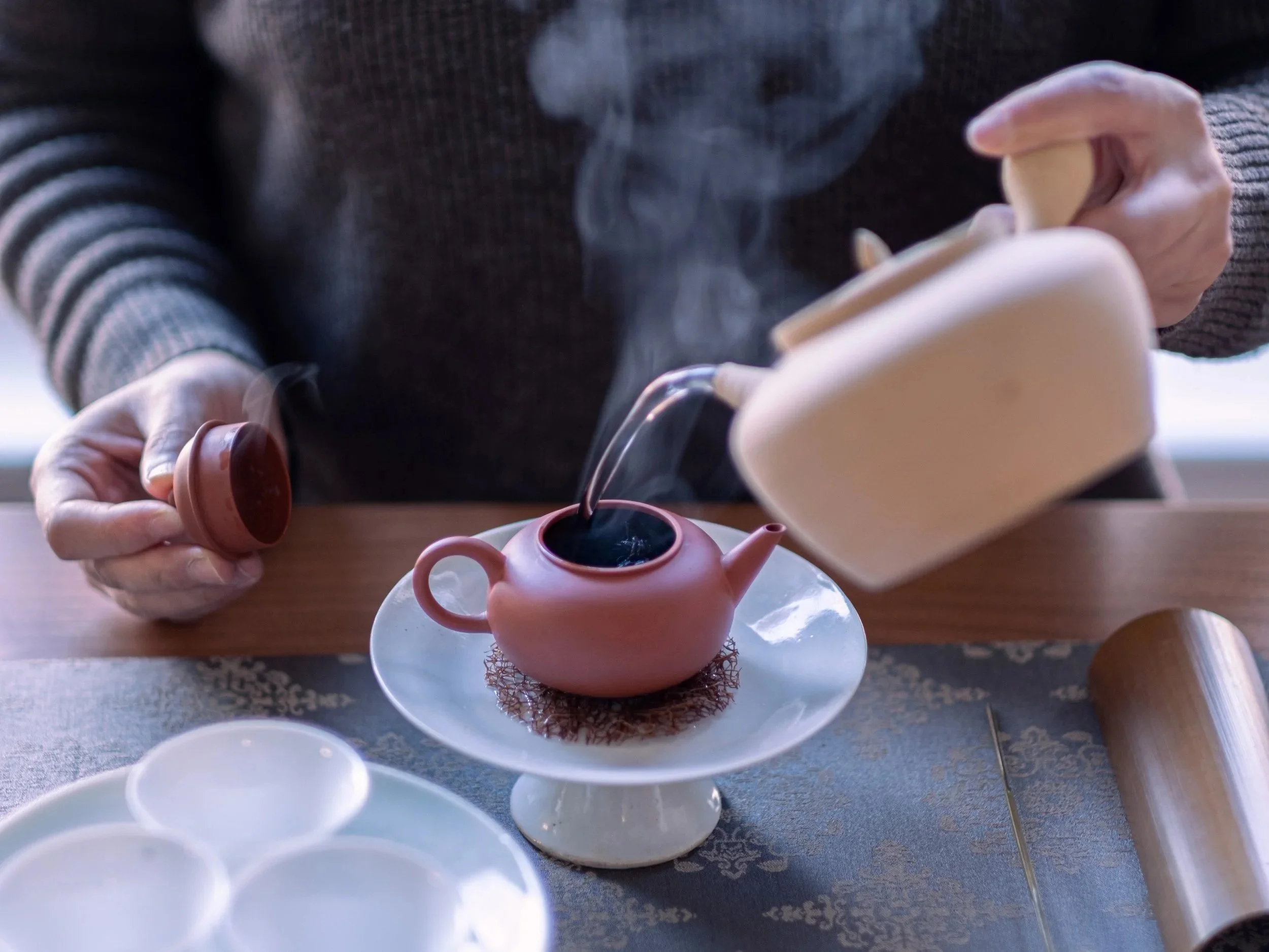Hot water is poured into a clay teapot on a quiet tea stage for Meditation with Tea.