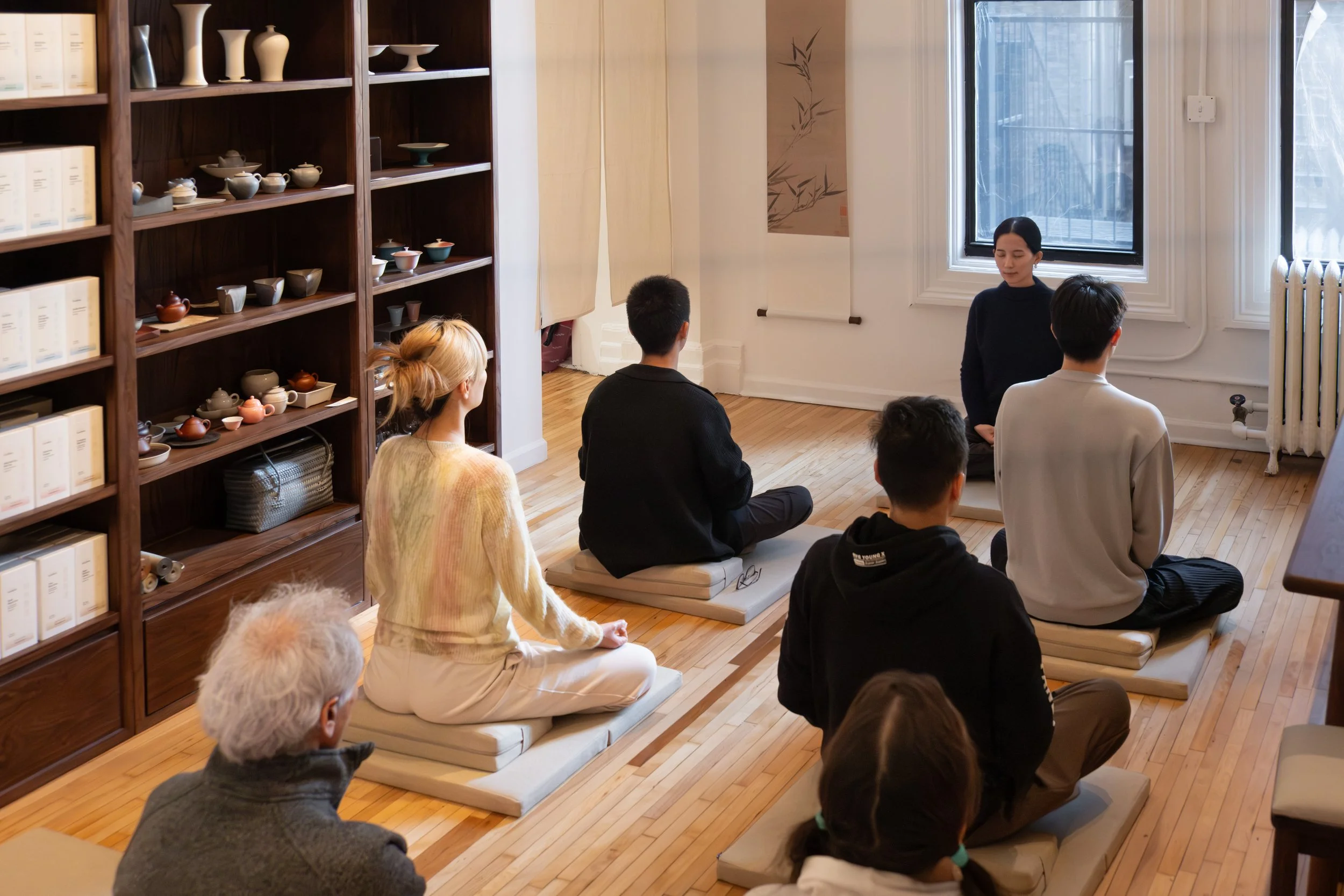 Guests sit on meditation cushions during guided meditation at Teasthetic.