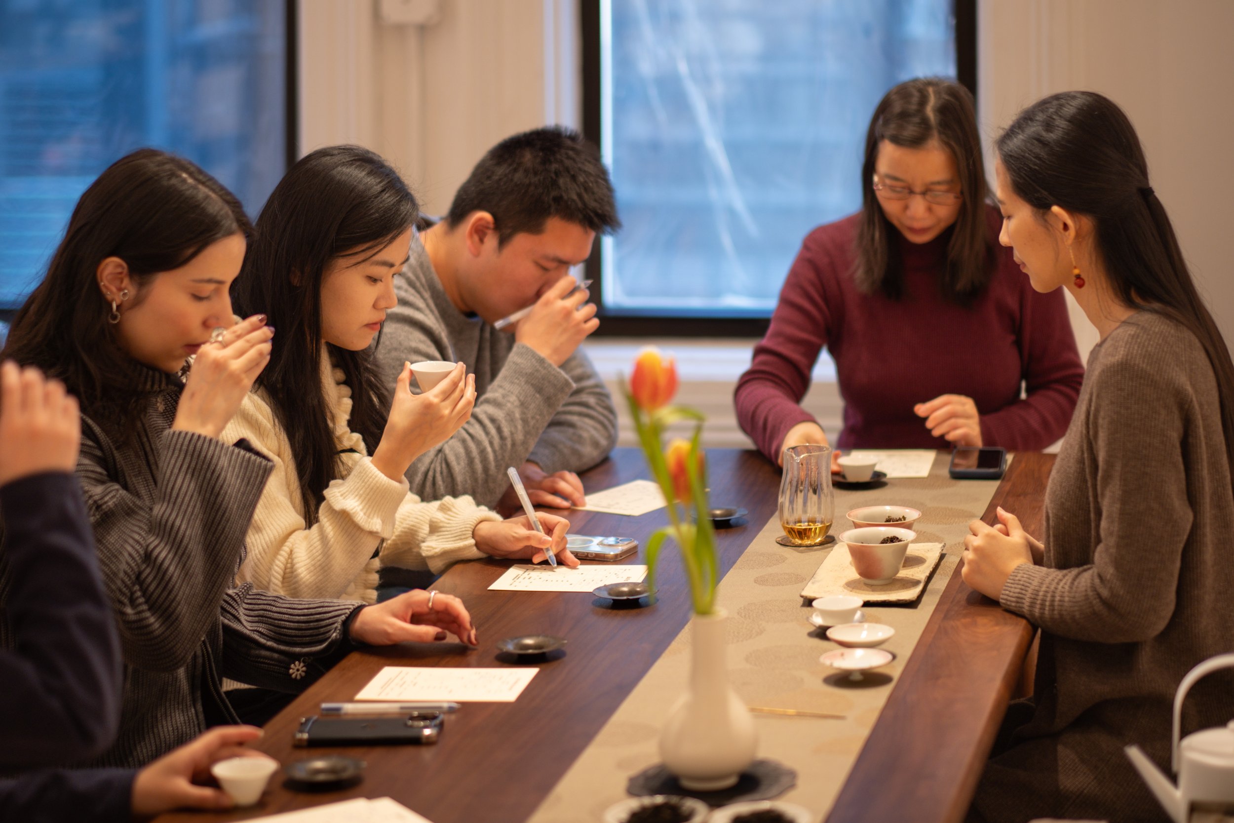 Guests taste tea and take notes in tea tasting journals during a Chinese tea tasting at Teasthetic.