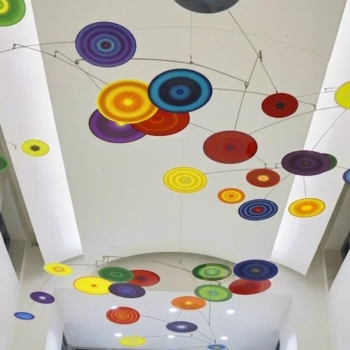 Vibrant colorful painted discs hanging mobile art lobby ceiling