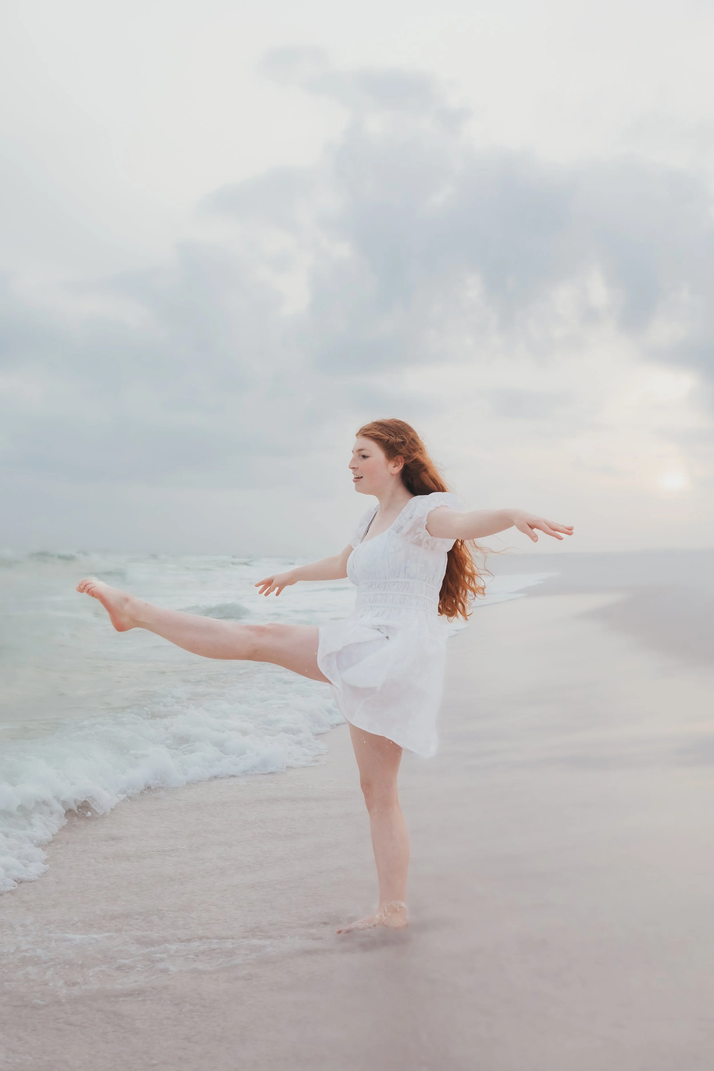A young girl dances at the water's edge in Destin, Florida. Taken by Destin Photographer June Sunrise Photography.