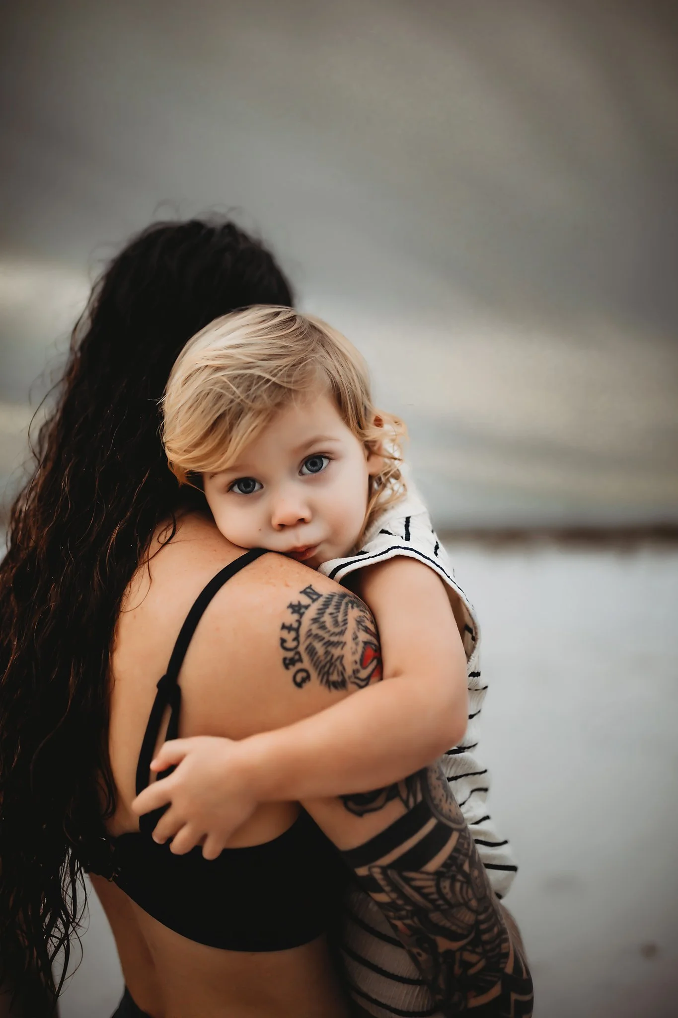 A mother comforts her toddler son as he gets sleepy from playing in the sand on the beach in Destin, Florida. Taken by Destin Photographer June Sunrise Photography.