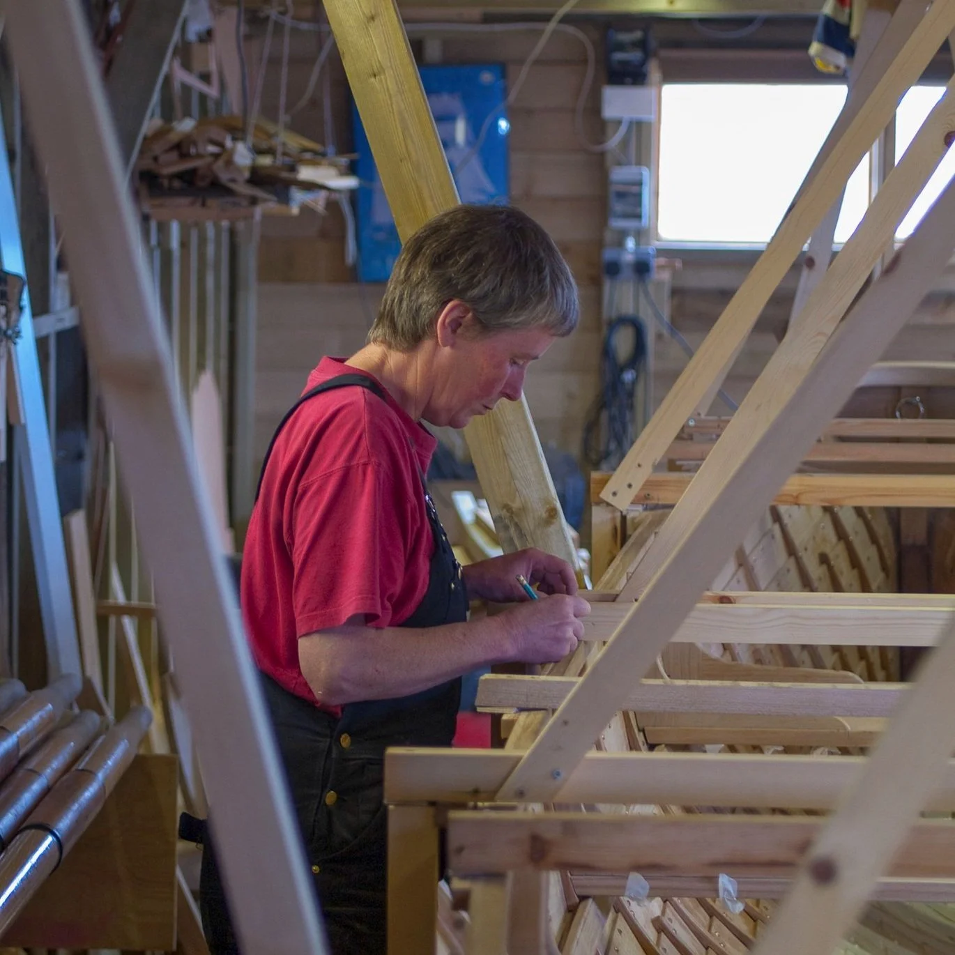 Gail McGarva, master boat builder, working on gig boat in workshop for Lyme Regis Gig Club in Dorset