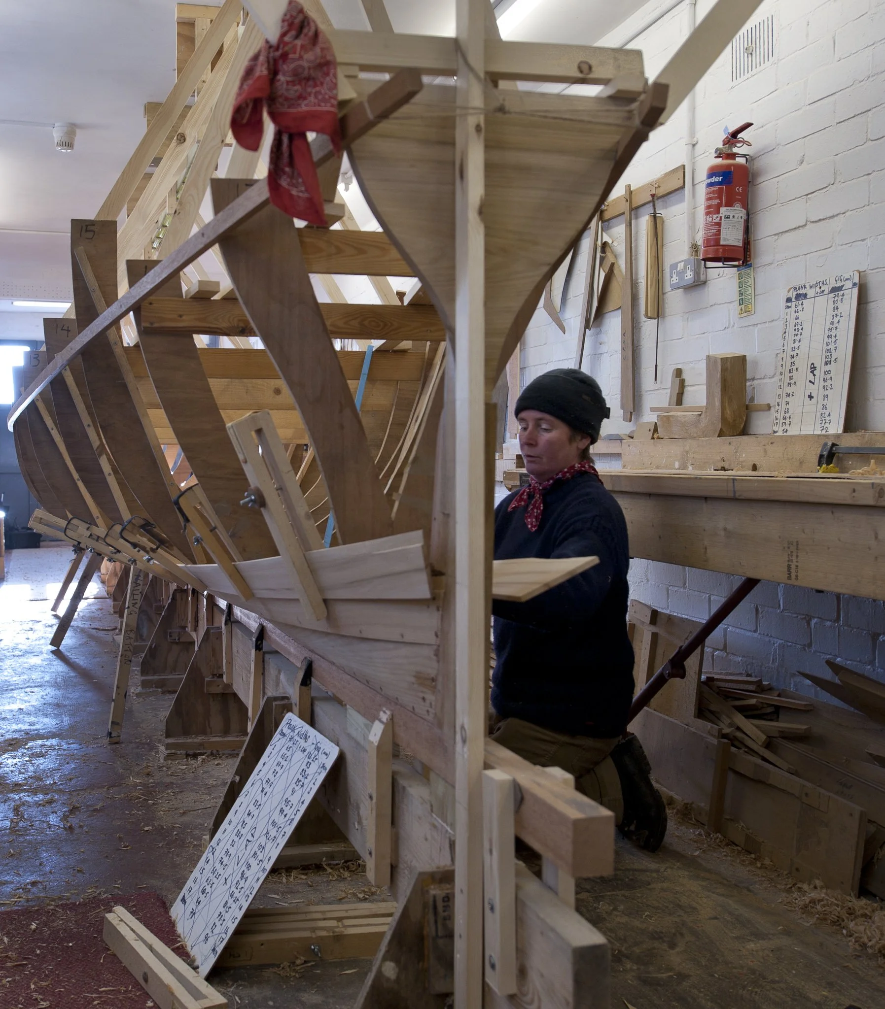 Professional commercial photography of Gail McGarva, boat builder in Dorset working on gig boat build in workshop